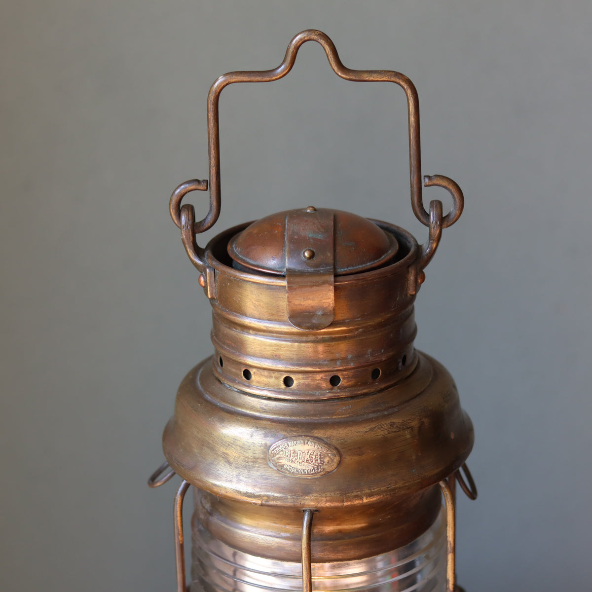 Close-up of Vintage Perko Ship’s Lantern – Anchor Light (Copper, Brass & Bronze) oil lamp detailing the brass handle and top.