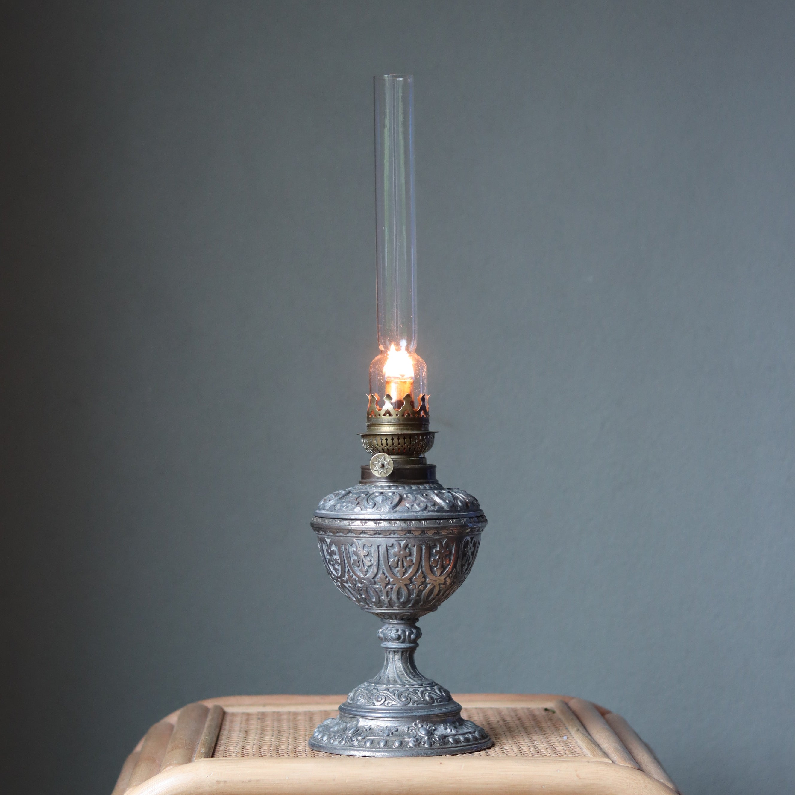 Vintage Decorative Oil Lamp – Metal Base & Glass Reservoir – Large Chimney – 1950s–1970s lit on woven surface against plain background