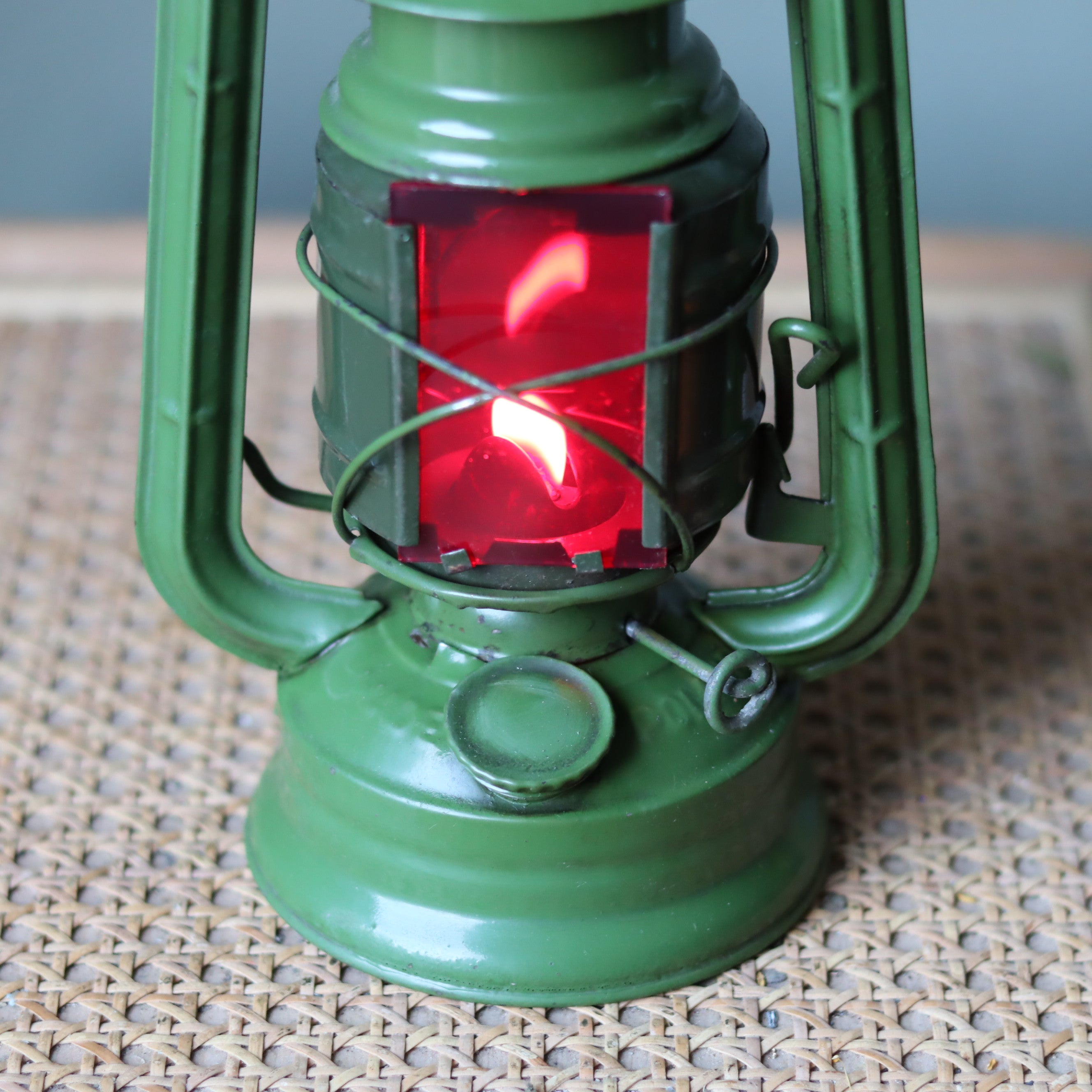 Rare Vintage Jupiter-1 Green Hurricane Lantern – Unique Flat Glass Holder with Red & Clear Panels oil lamp lit on woven surface