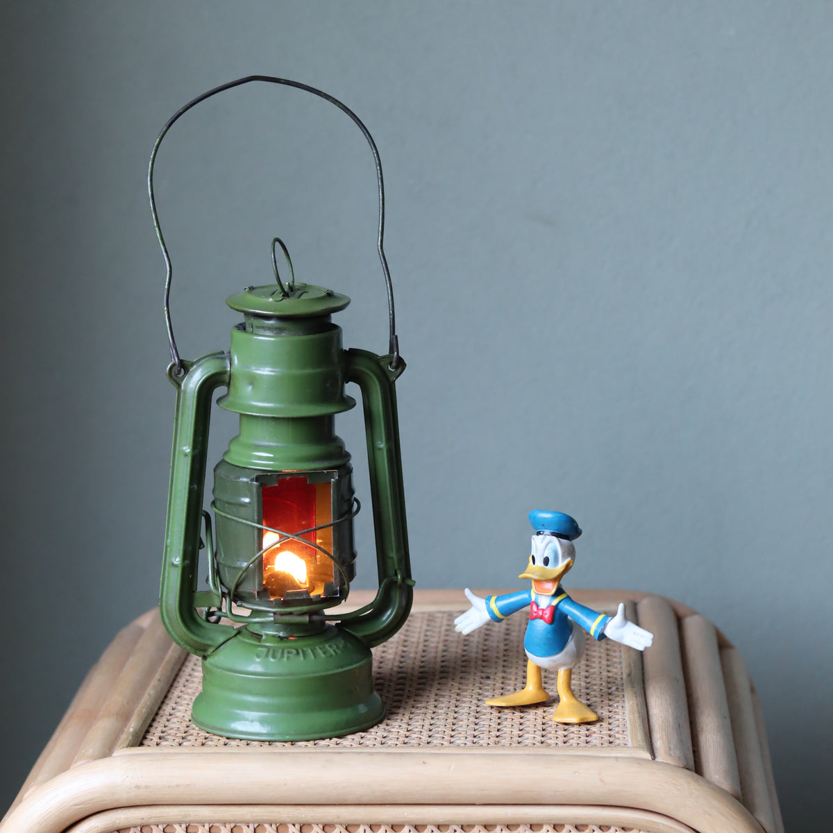 Rare Vintage Jupiter-1 Green Hurricane Lantern – Unique Flat Glass Holder with Red and Clear Panels oil lamp lit next to a toy figure