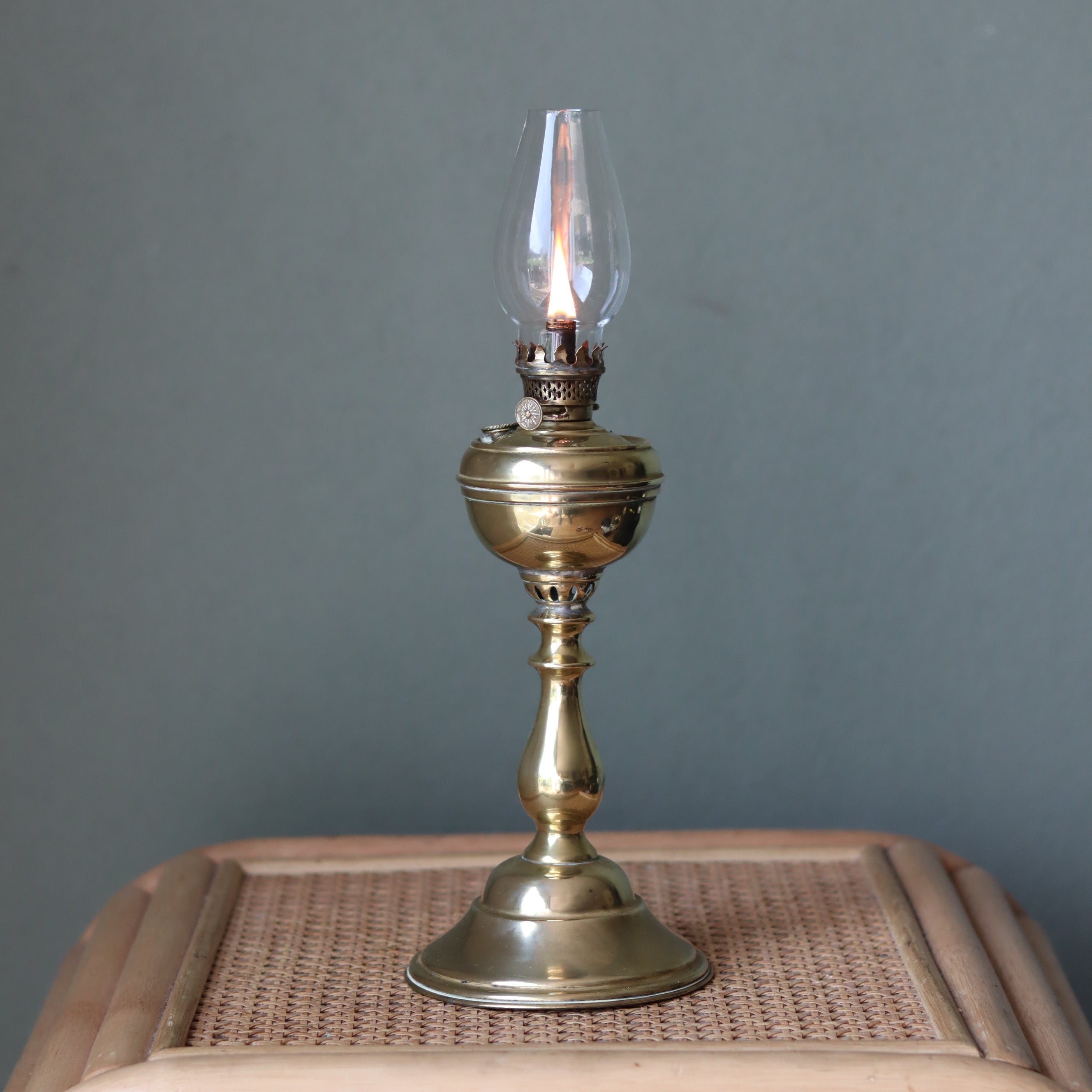 Rare Antique Oil Lamp with Unique Hollow Wick – Elegant Brass Design (c.1900–1930) standing lit on woven surface