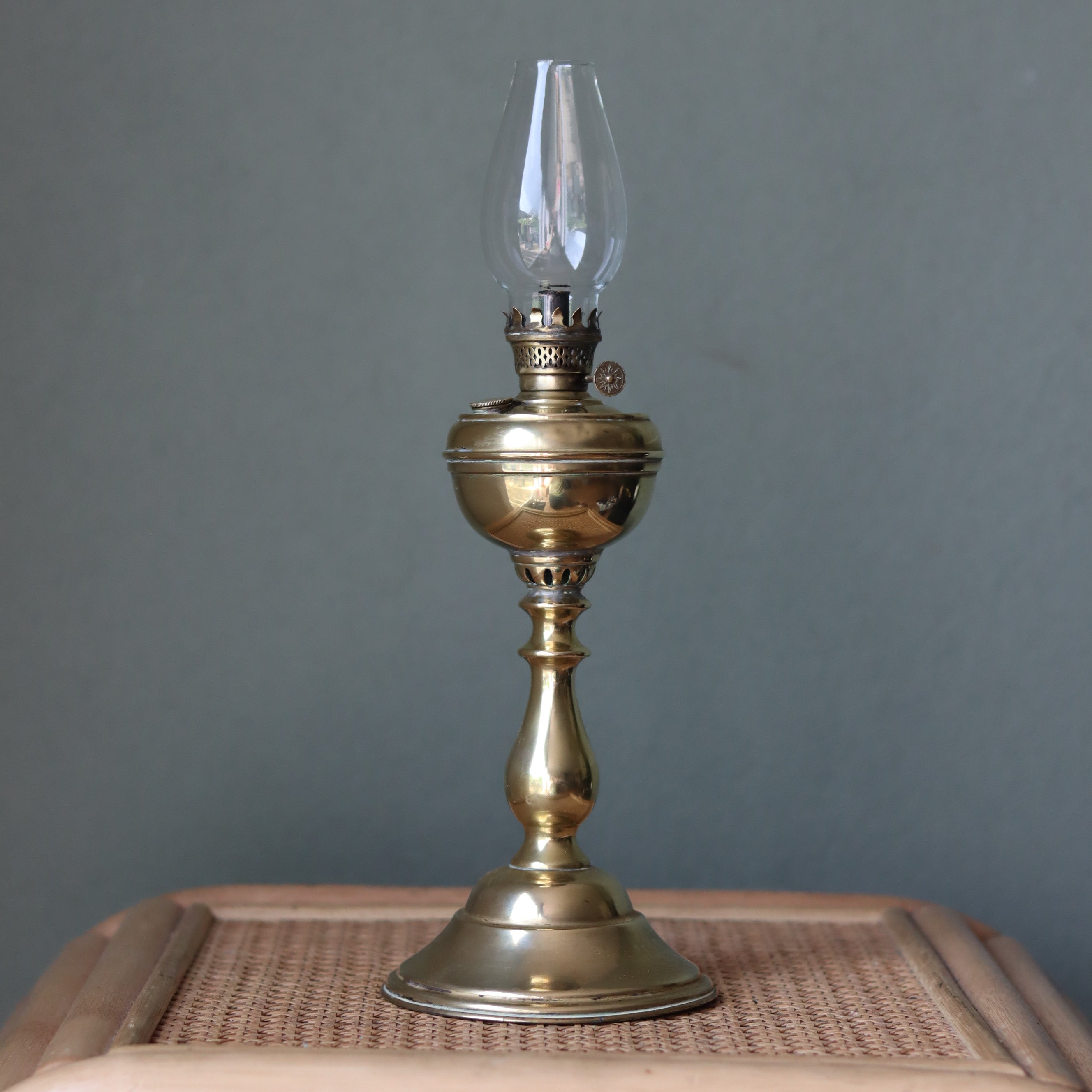 Rare Antique Oil Lamp with Unique Hollow Wick – Elegant Brass Design (c.1900–1930) standing on a wicker surface against gray background