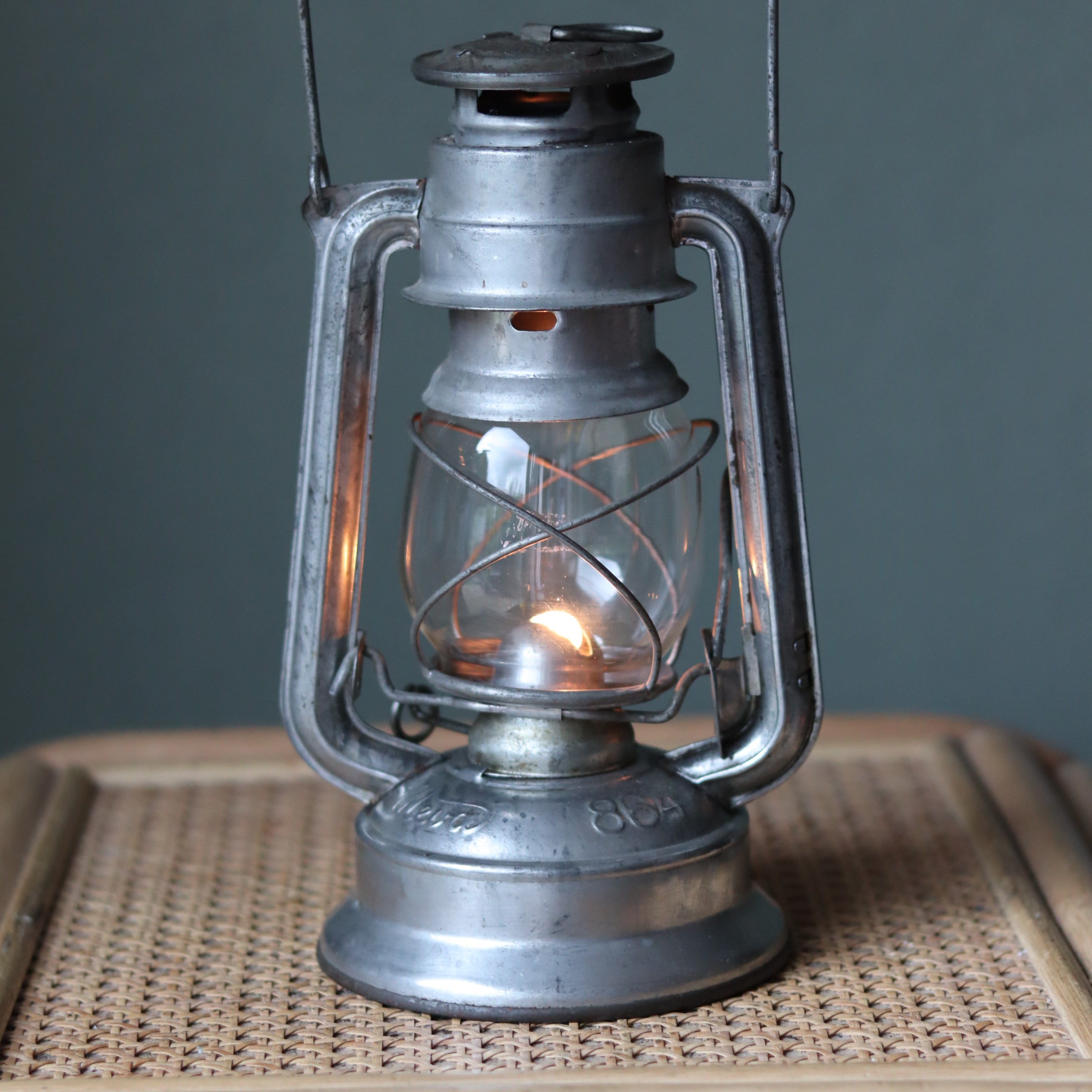 Vintage Mewa Hurricane Lantern – Model 864 (1978) showcasing classic metal oil lamp design with lit flame inside glass enclosure