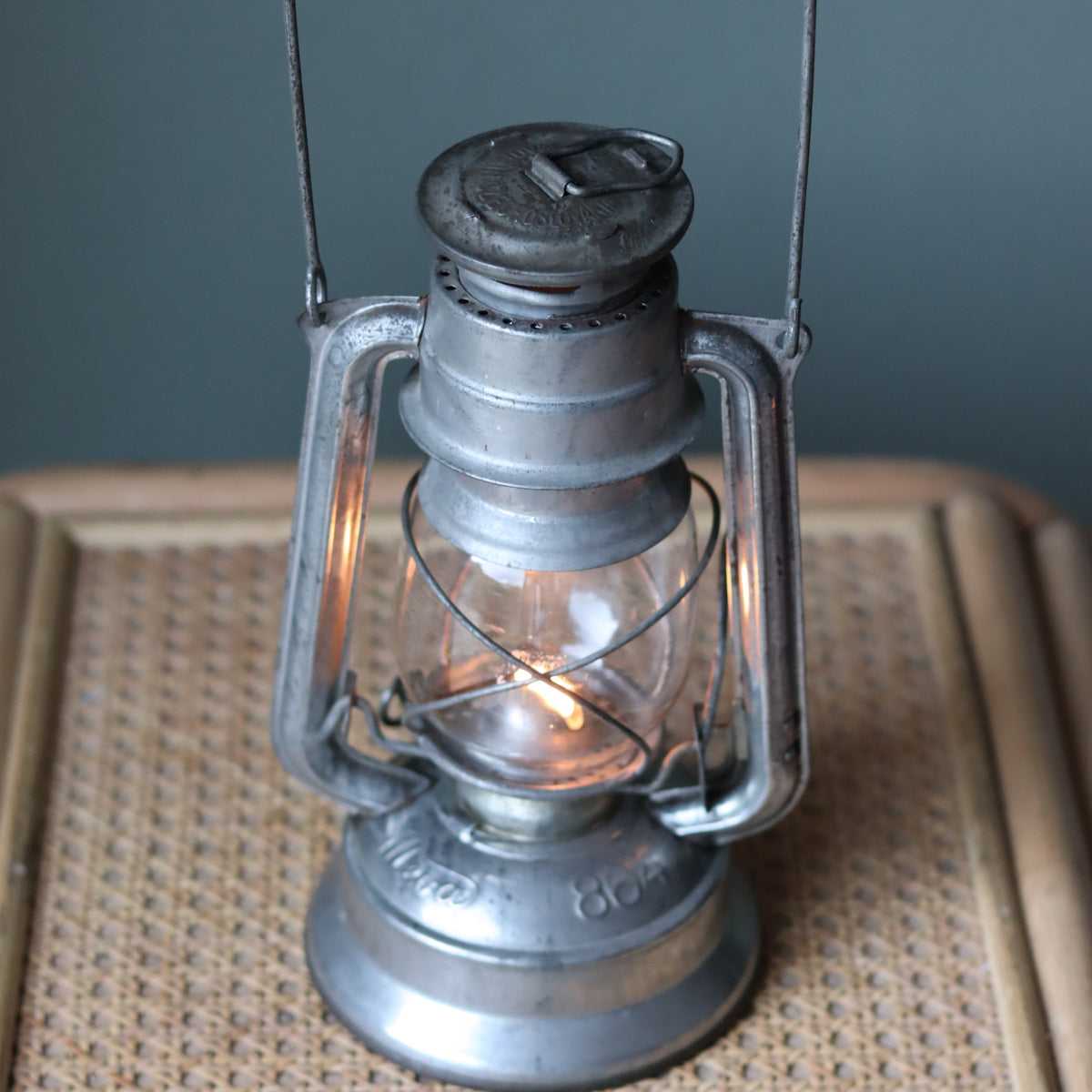 Vintage Mewa Hurricane Lantern – Model 864 (1978) displaying classic metal oil lamp design with lit flame inside glass enclosure