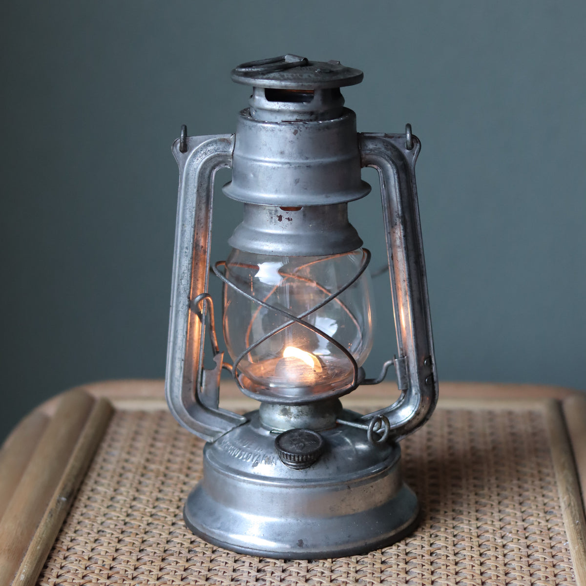 Vintage Mewa Hurricane Lantern – Model 864 (1978) old oil lamp with lit flame, showcasing classic metal and glass design.