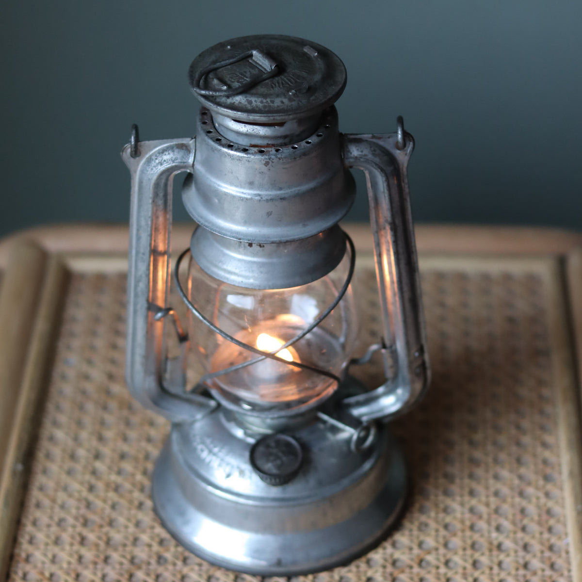 Vintage Mewa Hurricane Lantern – Model 864 (1978) classic oil lamp with metal frame and glass chimney lit on a woven surface