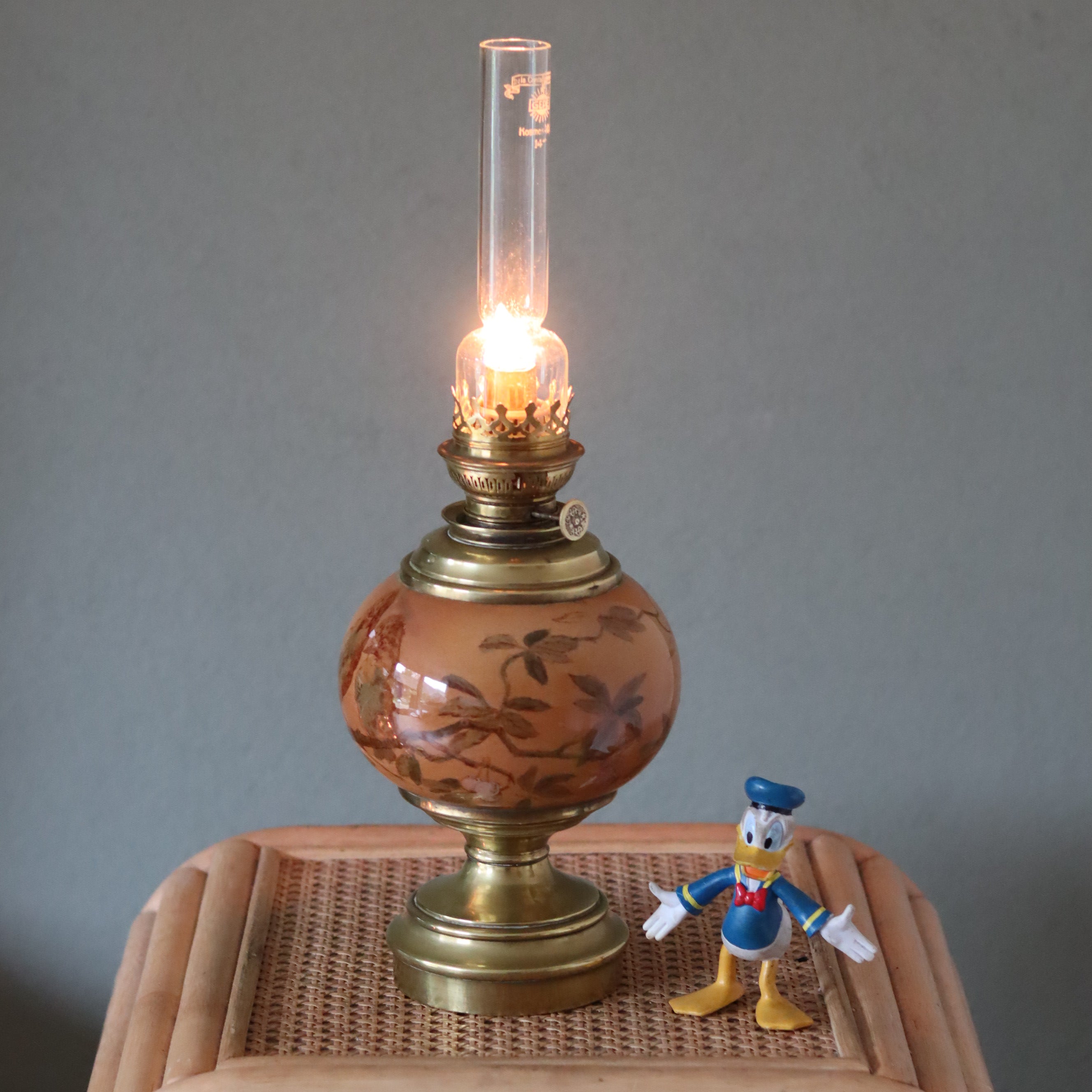 Rare Vintage French Oil Lamp – SI Paris Burner – Brass Base & Porcelain Reservoir with Birds – 1930s lit on table next to a toy figure