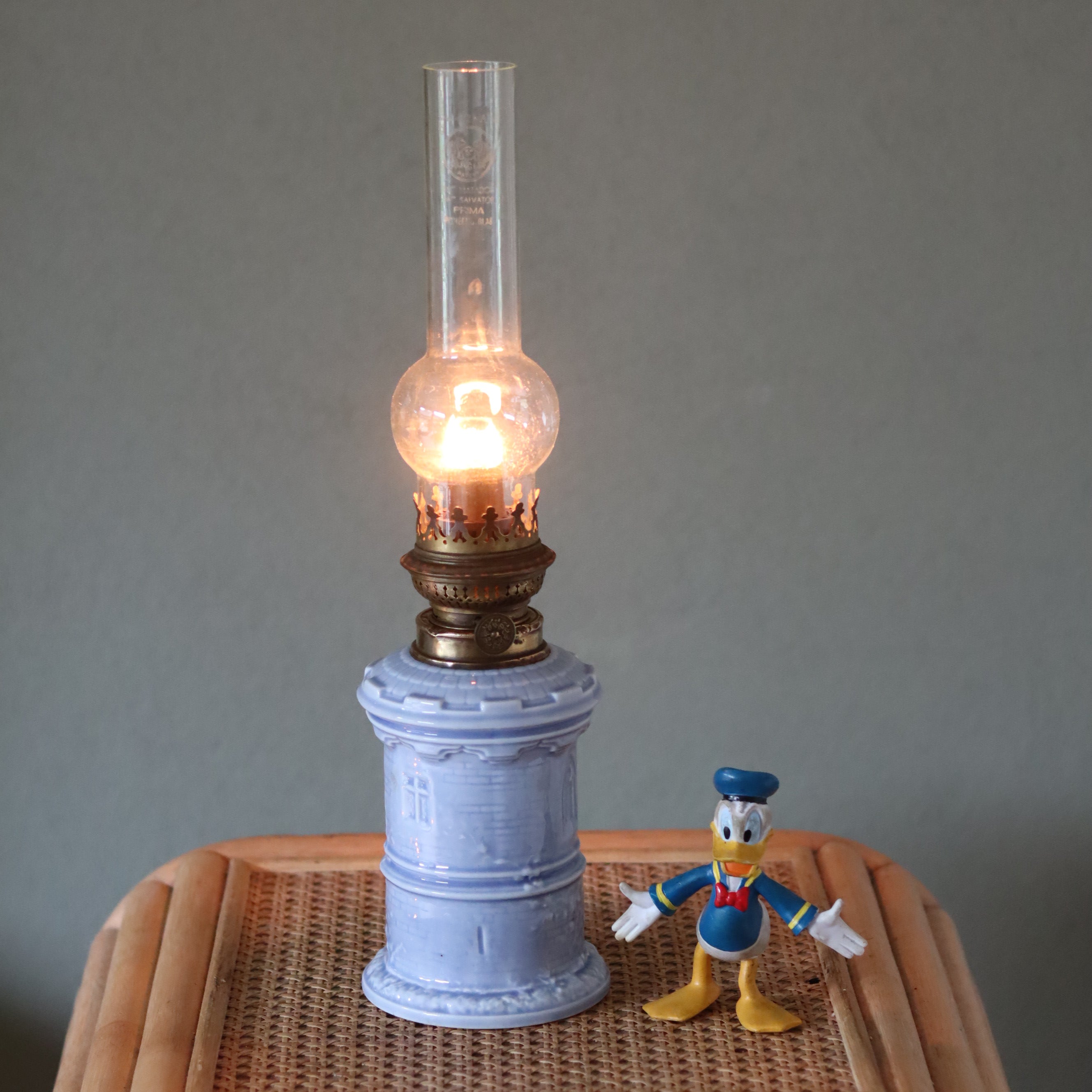 Rare Vintage Ceramic Oil Lamp – Tower Design with Wild & Wessel Burner (1930s) lit on a wicker surface