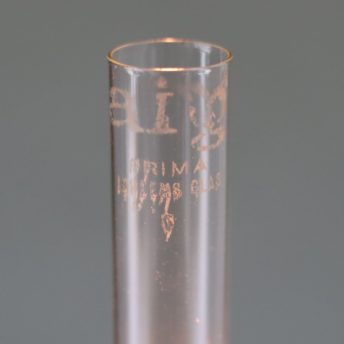 Close-up of a clear glass chimney from the Vintage Oil Lamp with Wild & Wessel Burner – 1930s showing faded brand markings.