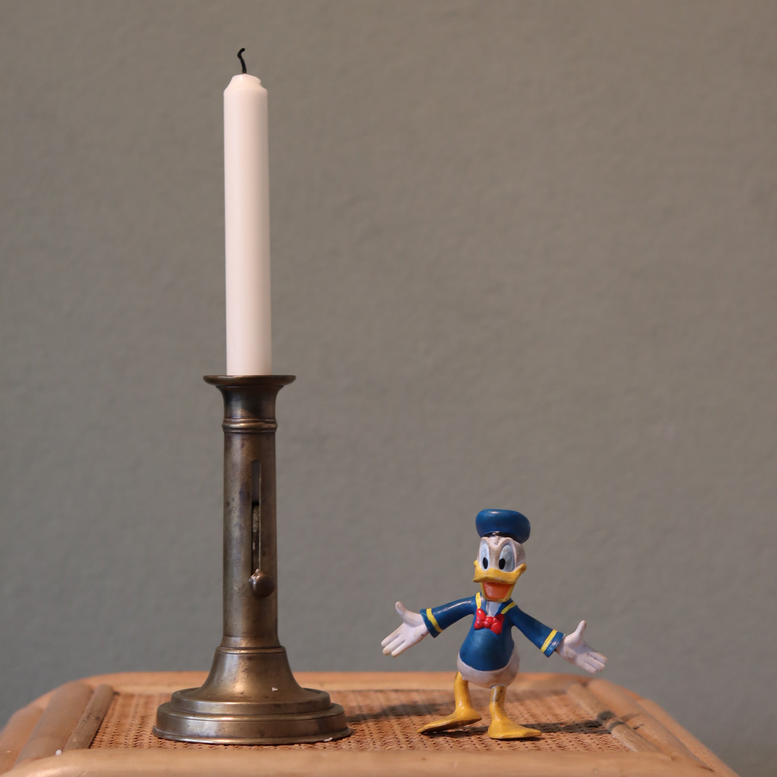 Vintage Bronze Candlestick with Adjustable Slide – Includes Candle – 1930s–1950s with a tall white candle on a wooden surface