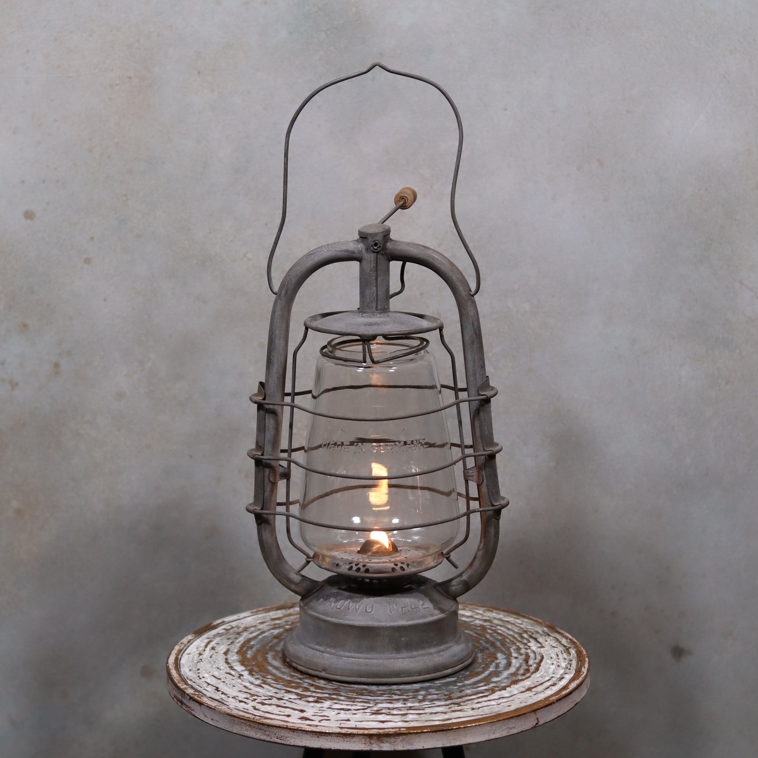 Restored Frowo 420 Storm Lantern – German vintage oil lamp with original marked glass in excellent condition lit on rustic table.