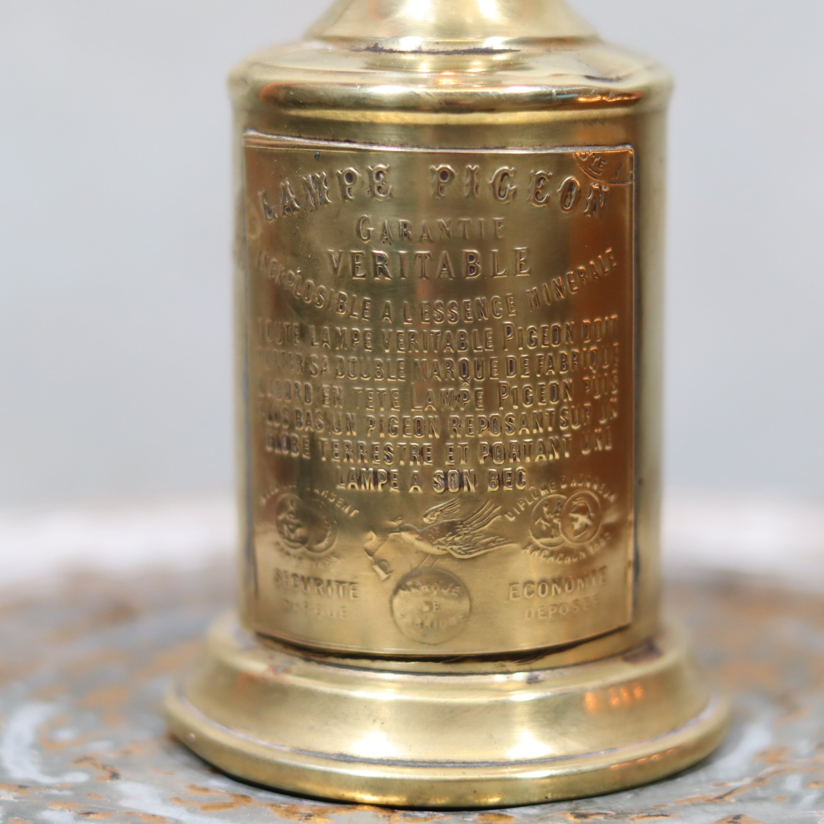 Rare Antique Oil Lamp – Early Pigeon Lamp (Circa 1900) close-up of engraved gold metal branding details on lamp body