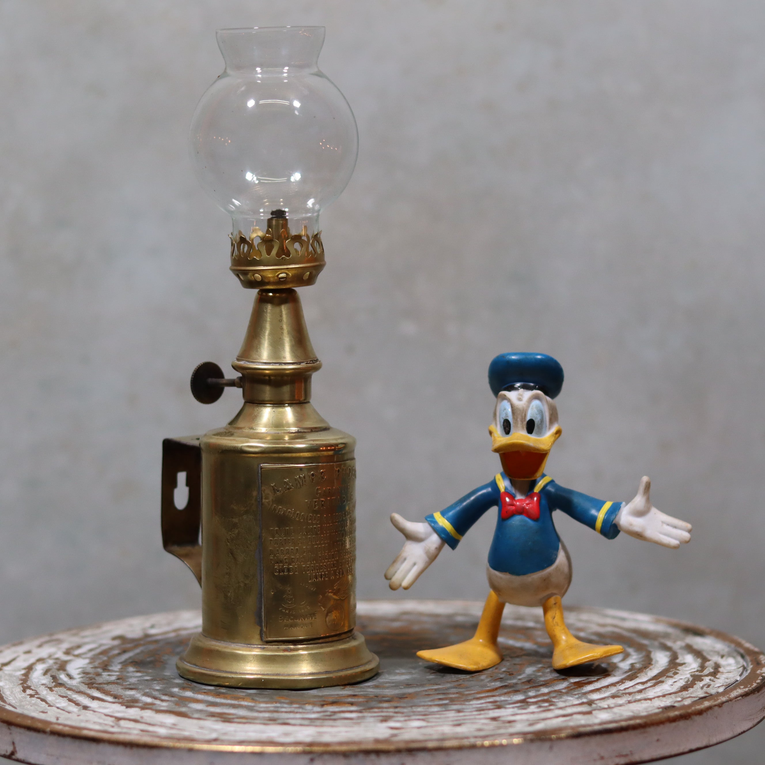 Rare Antique Oil Lamp – Early Pigeon Lamp (Circa 1900) with brass body and glass chimney displayed on rustic surface