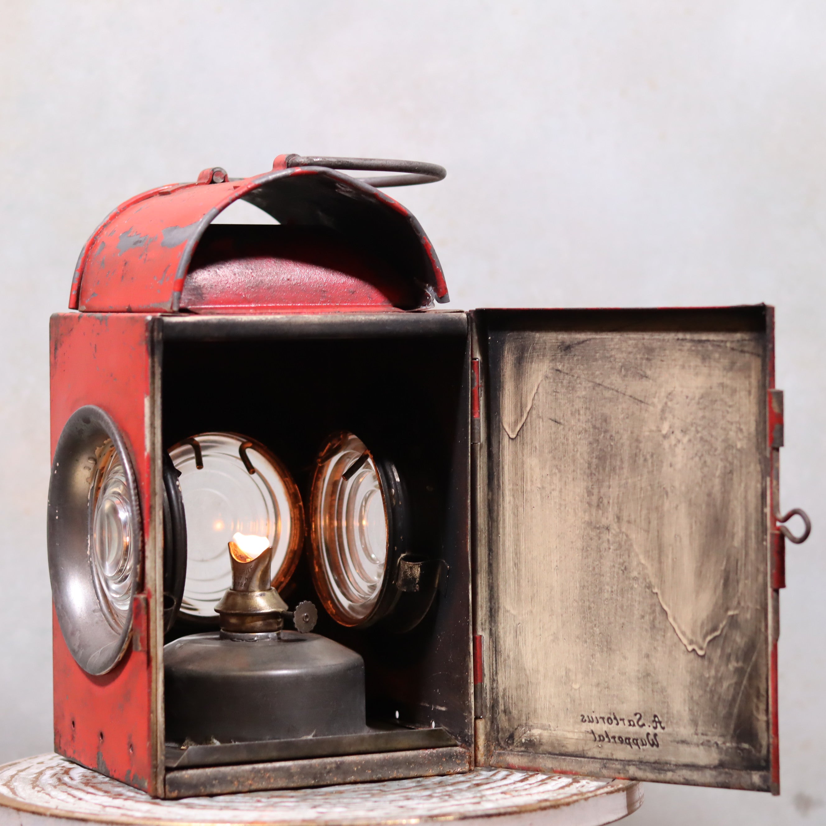 Vintage Roadwork Oil Lamp – A. Sartorius Wuppertal with Fishtail Burner (1960s) showing lit burner inside red metal case