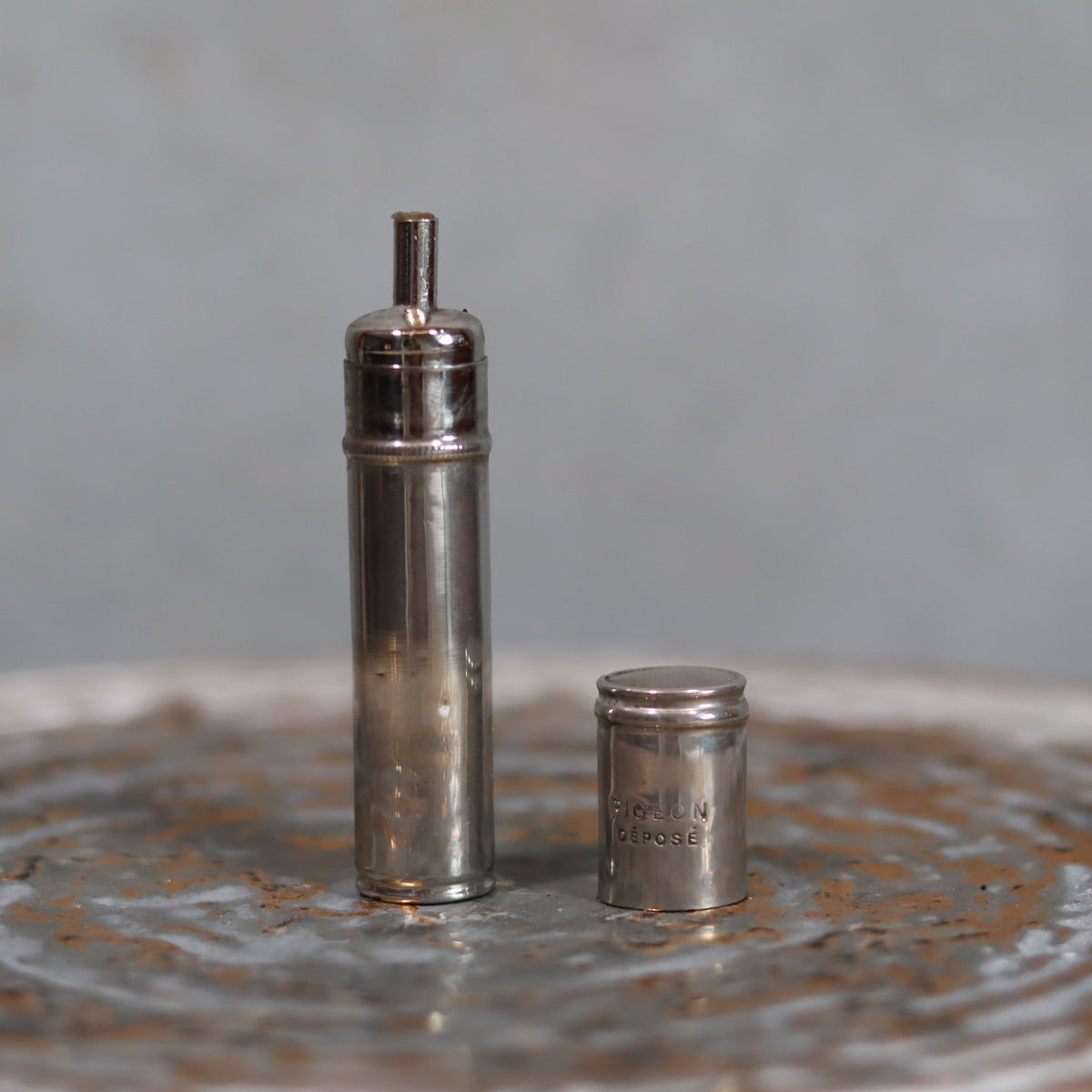 Rare Antique Pigeon Pocket Oil Lamp – Model 60, Complete and Functional, Circa 1918–1930 shown with its metal components on a textured surface