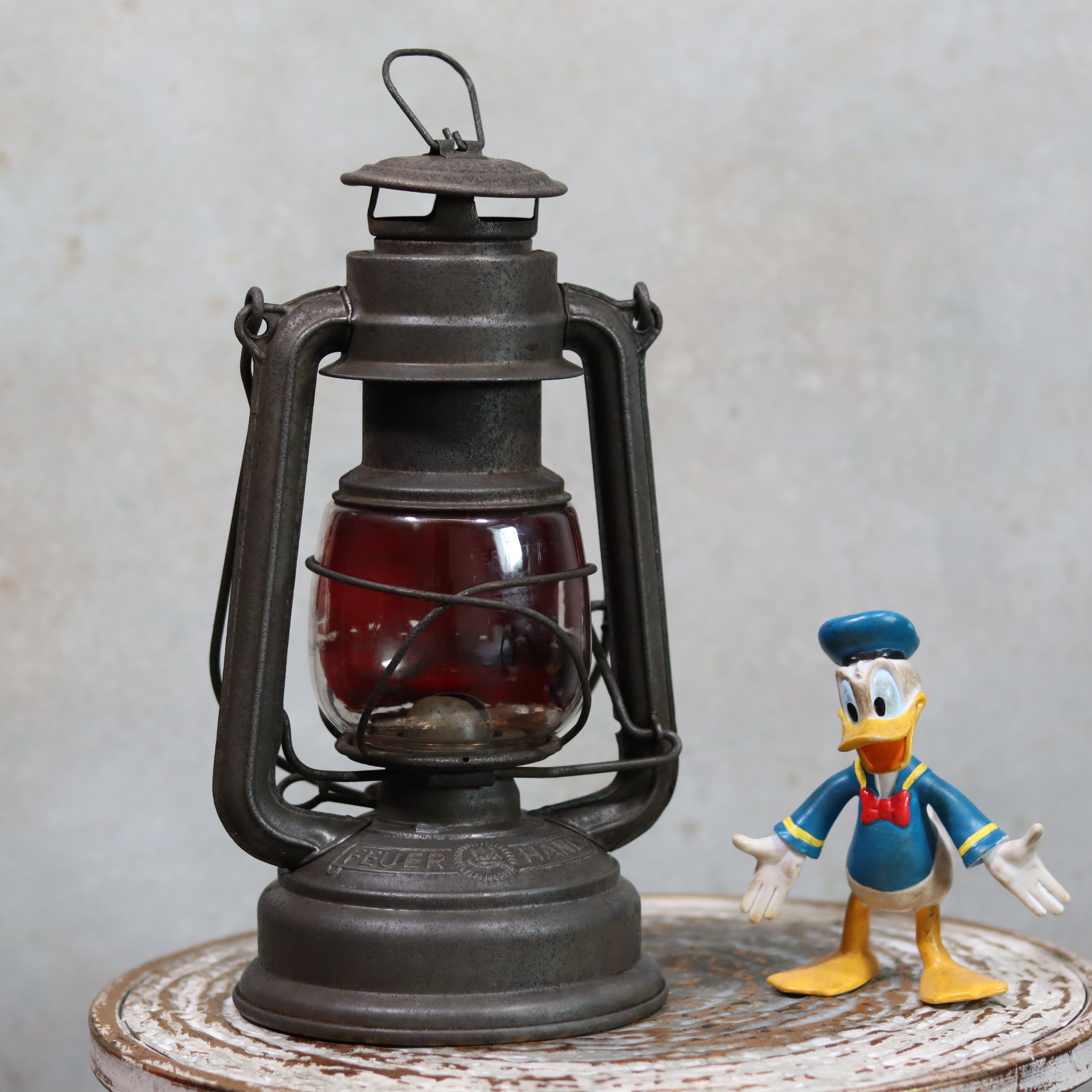 Vintage Feuerhand Hurricane Lantern – Model 276 (1950s) with rare glass oil lamp showing classic metal frame and deep red glass.