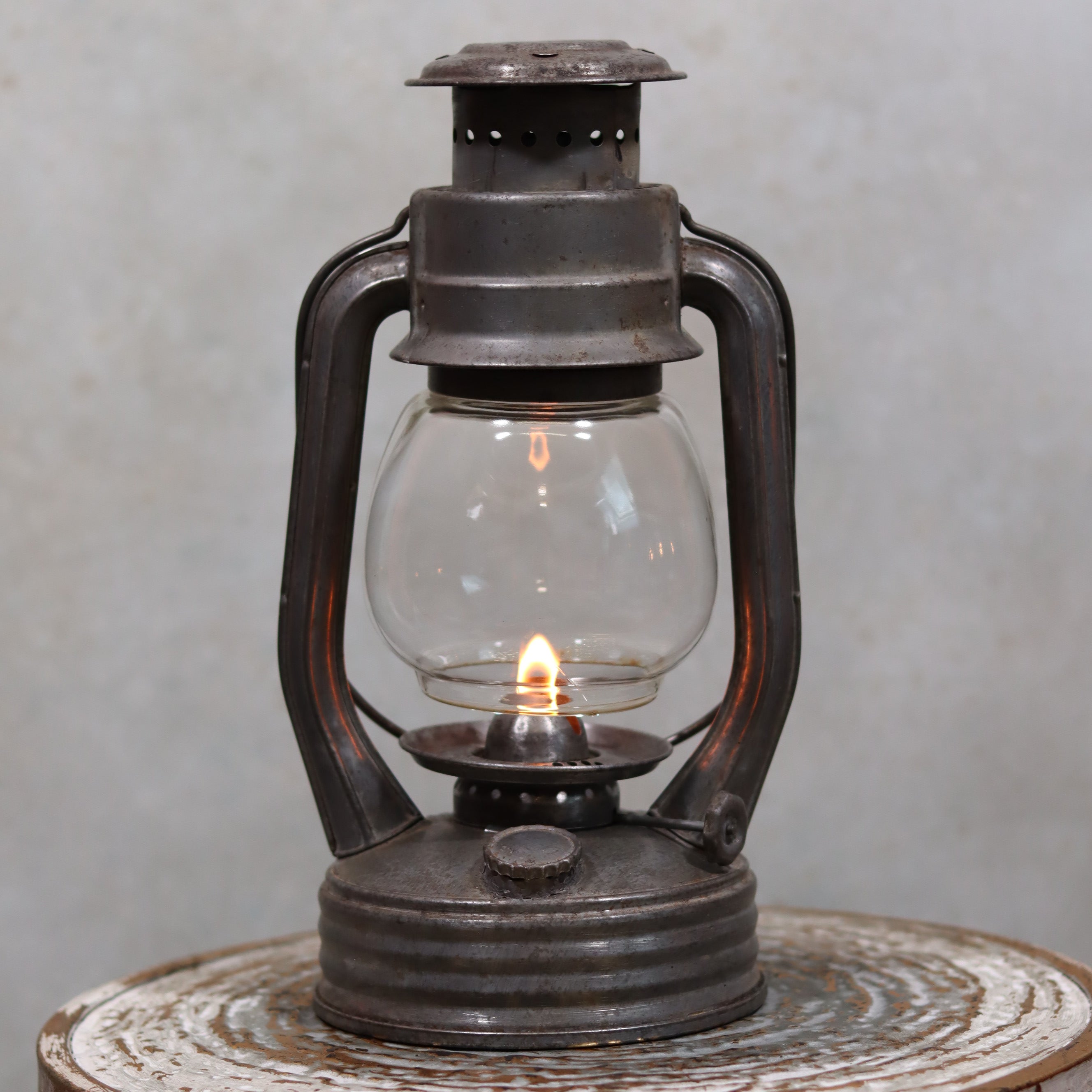 Vintage French Royalux Hurricane Lantern – Glass Lift Mechanism (27 cm) with lit oil lamp and rustic metal frame.