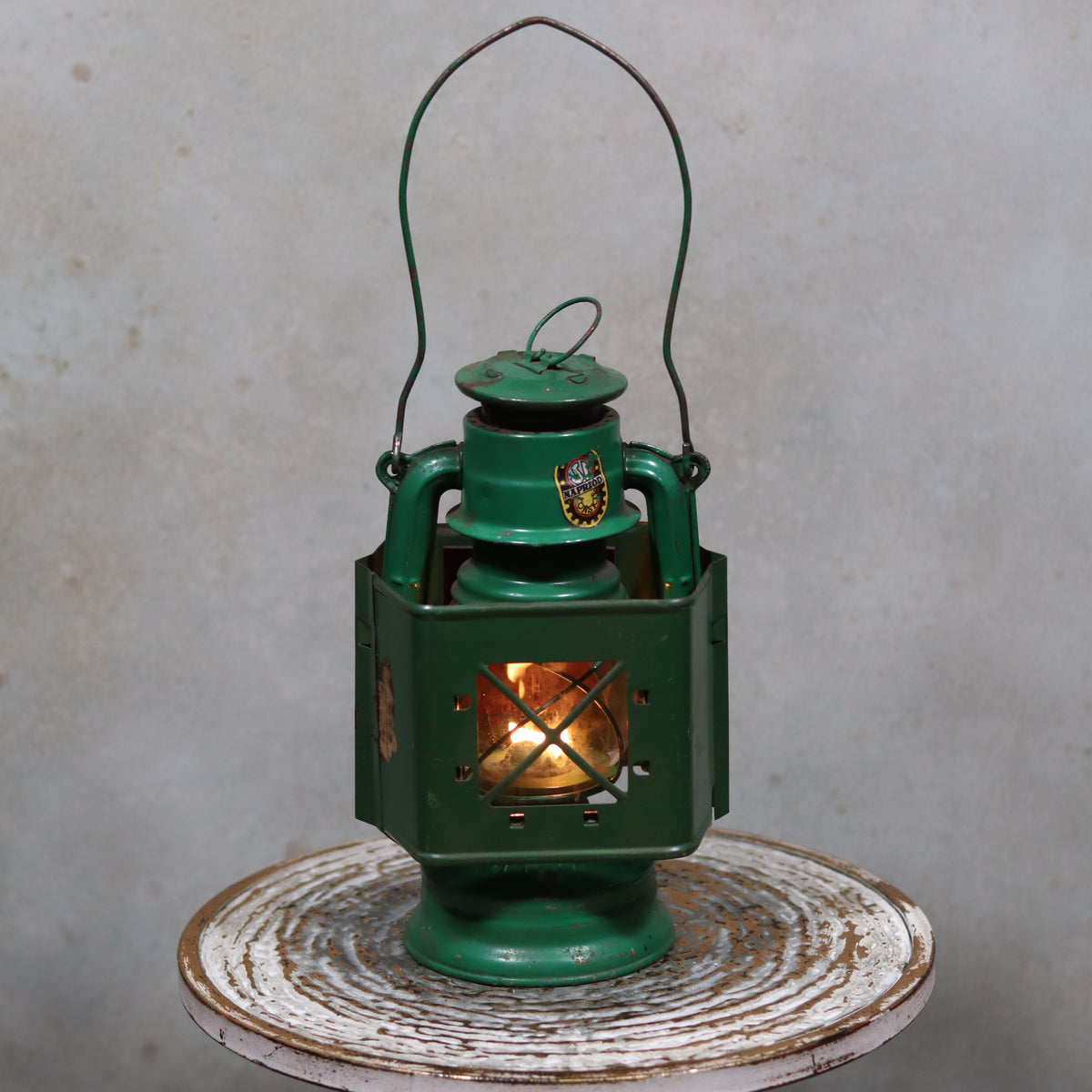 Rare Vintage Jupiter-1 Green Hurricane Lantern – With Unique Glass Holder & Original Sticker oil lamp lit on rustic table