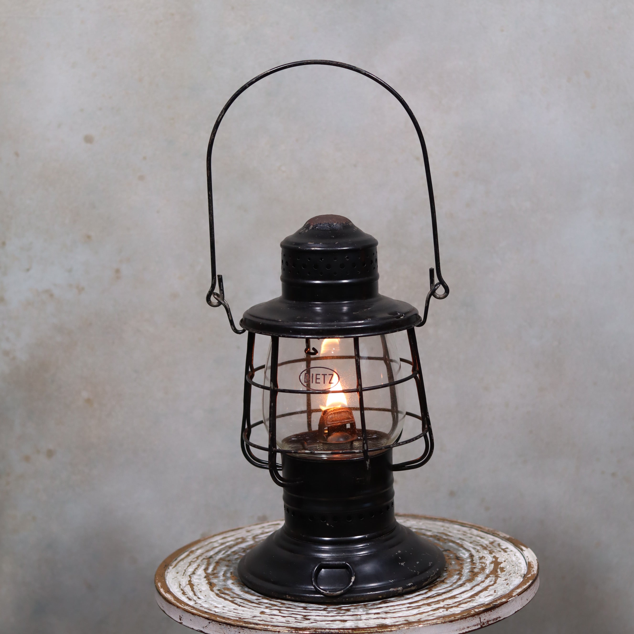 Vintage Keystone Ware Hurricane Lantern – Black Finish with Dietz Glass oil lamp lit on rustic surface