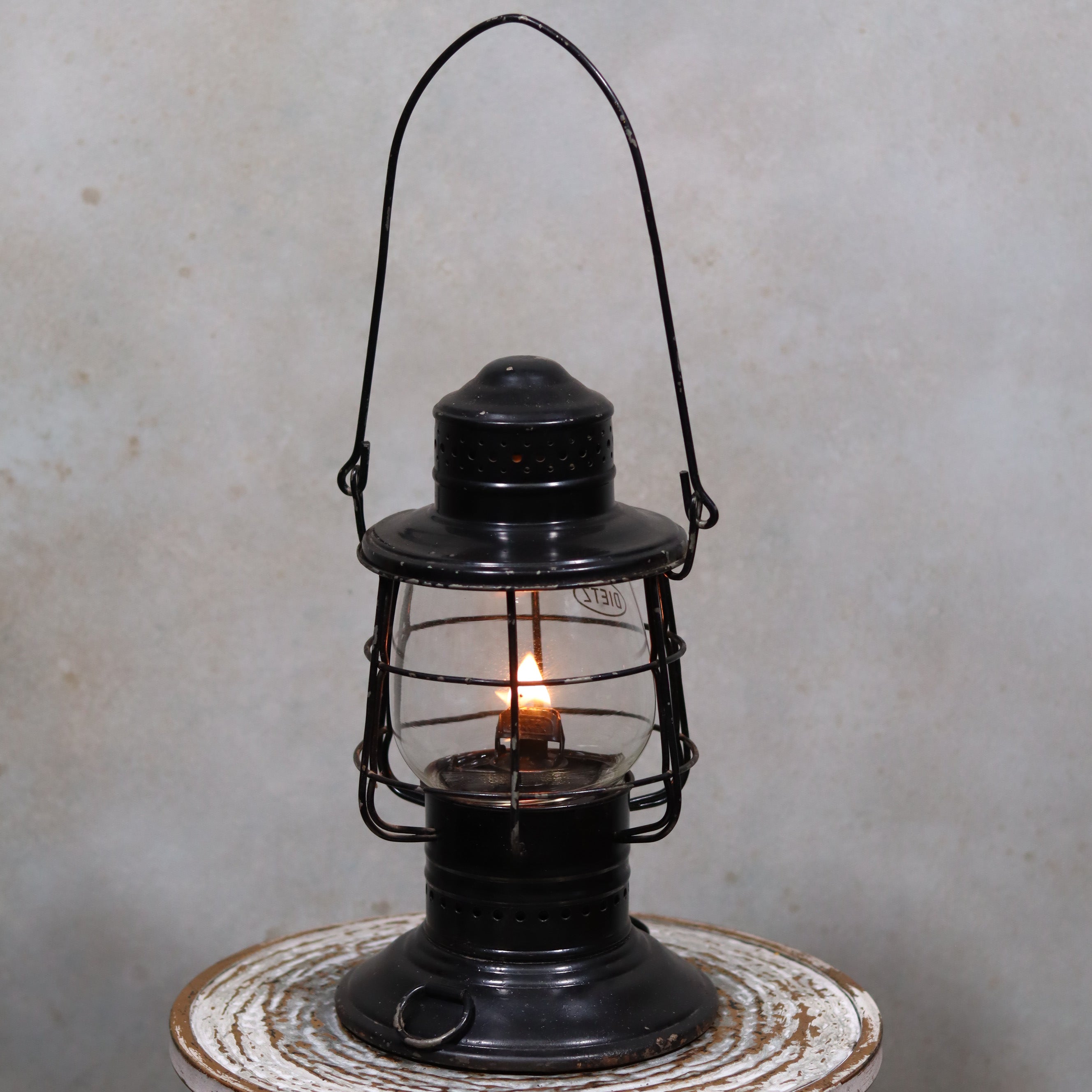 Vintage Keystone Ware Hurricane Lantern – Black Finish with Dietz Glass showing a lit vintage oil lamp with protective metal frame