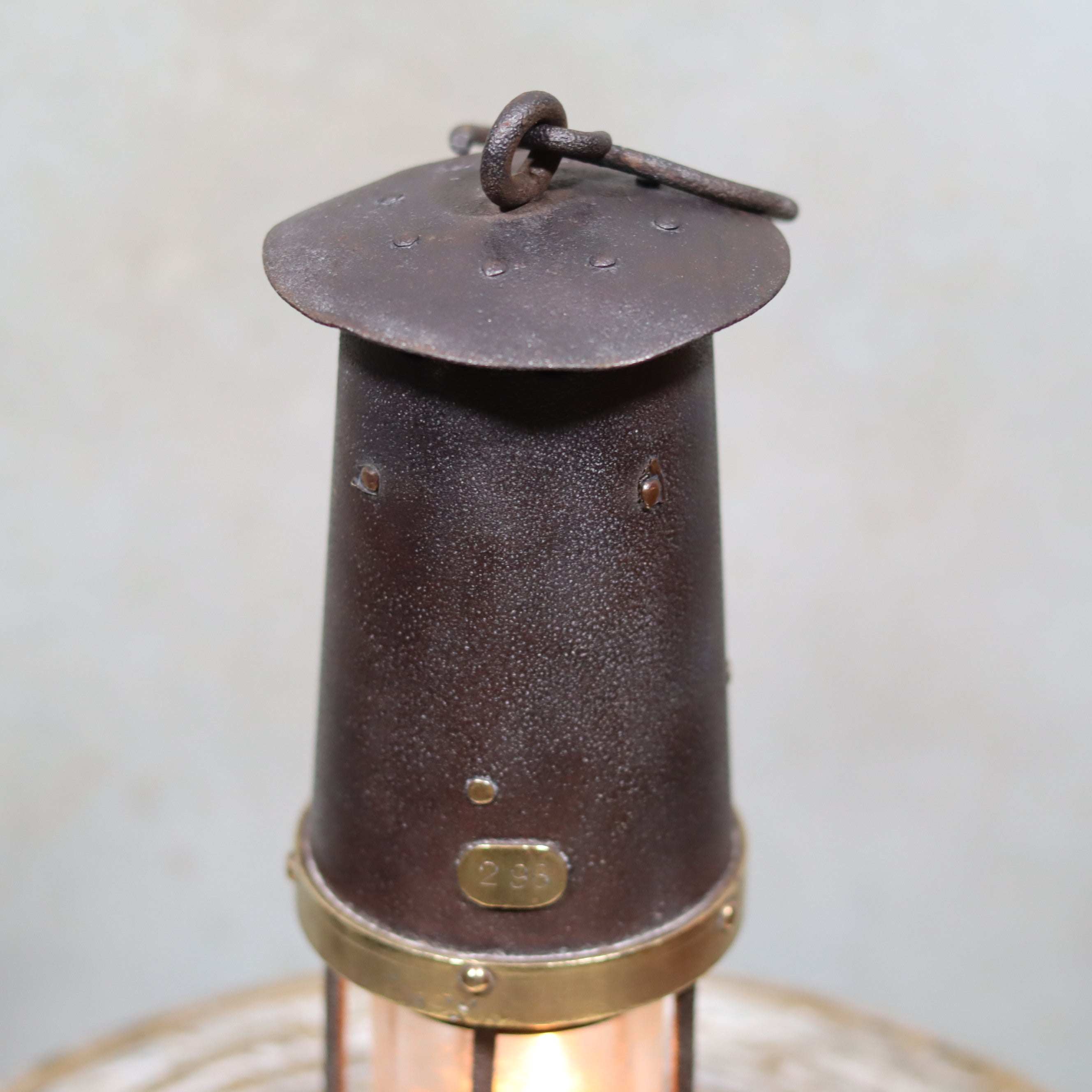 Antique British Mining Lamp – Davies Derby Safety Lamp (Circa 1900) featuring the oil lamp’s metal top and brass band design.