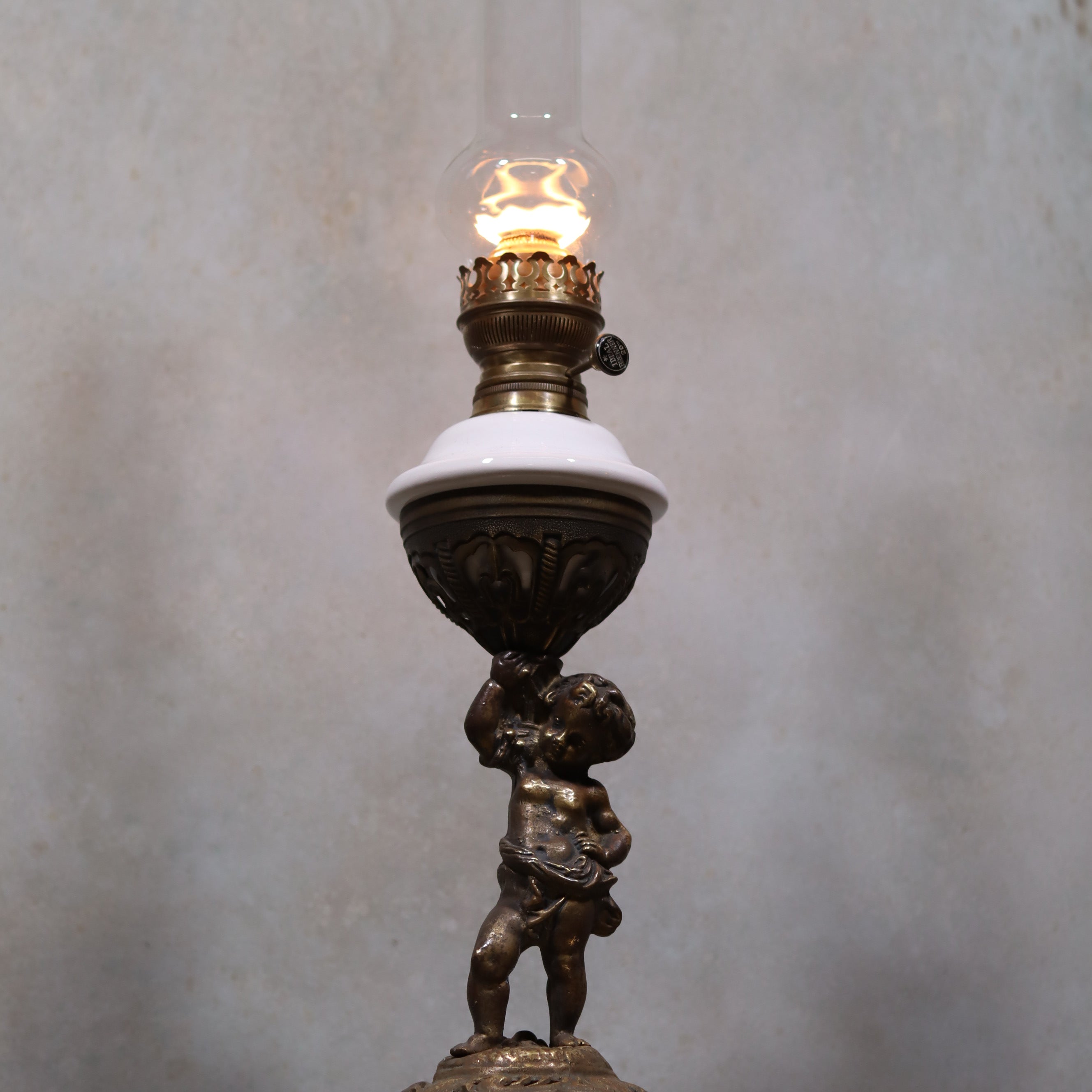 Vintage XXL Oil Lamp with BJB Matador Burner – Bronze Base with Cherub Design lit against gray background