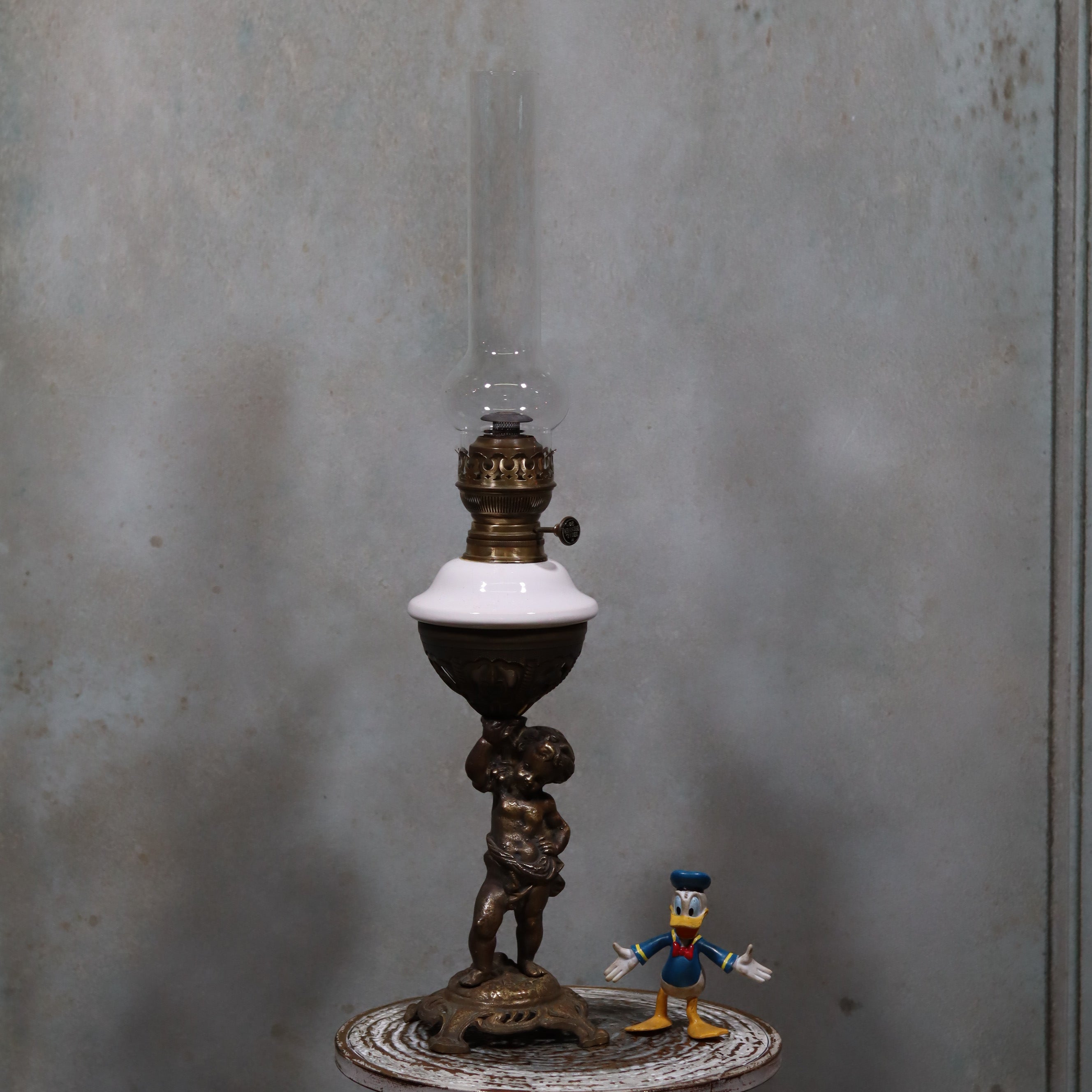 Vintage XXL Oil Lamp with BJB Matador Burner – Bronze Base with Cherub Design standing on a vintage table
