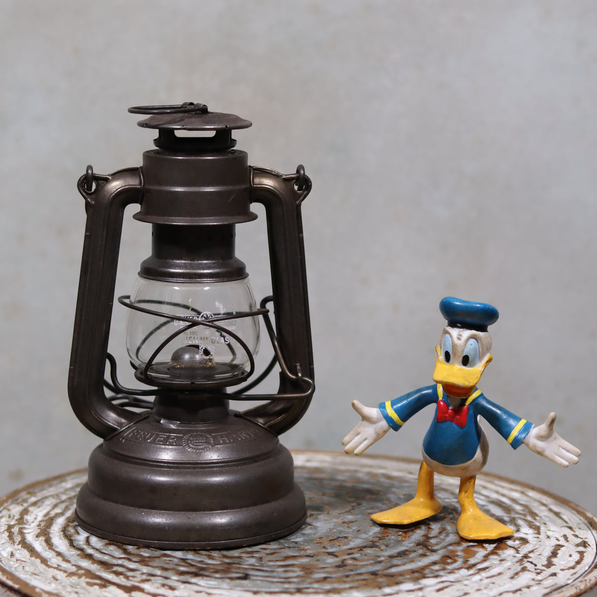 Vintage Feuerhand 176 Storm Lantern – Post-WWII Model, 1950s, Excellent Condition oil lamp on rustic surface with Donald Duck figure next to it