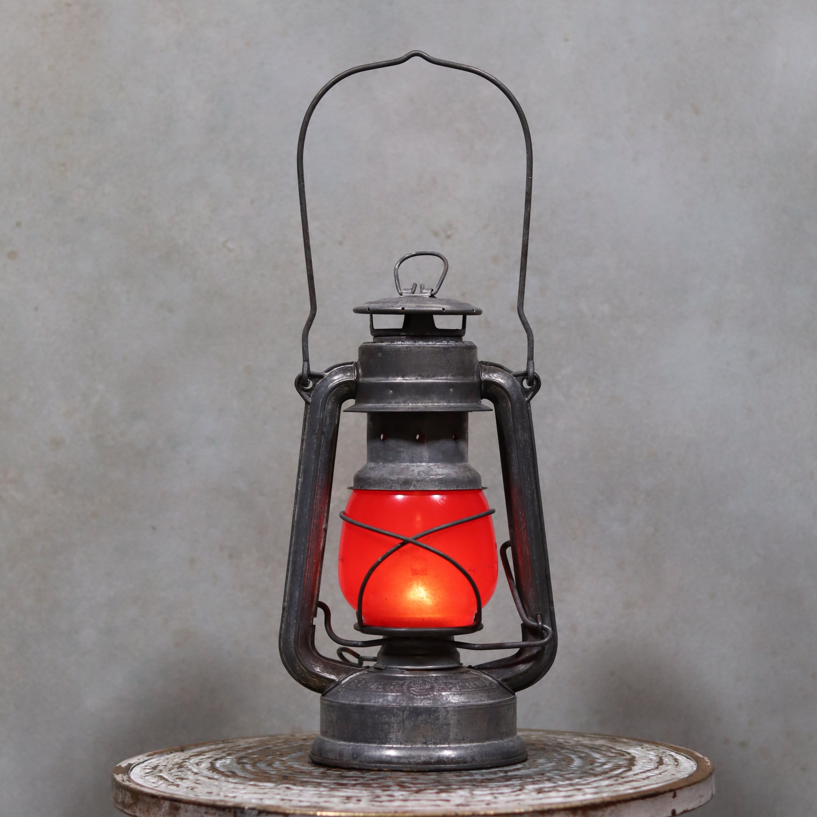 Vintage Feuerhand Baby 275 Hurricane Lantern – Western Germany – Red Glass oil lamp glowing on rustic surface