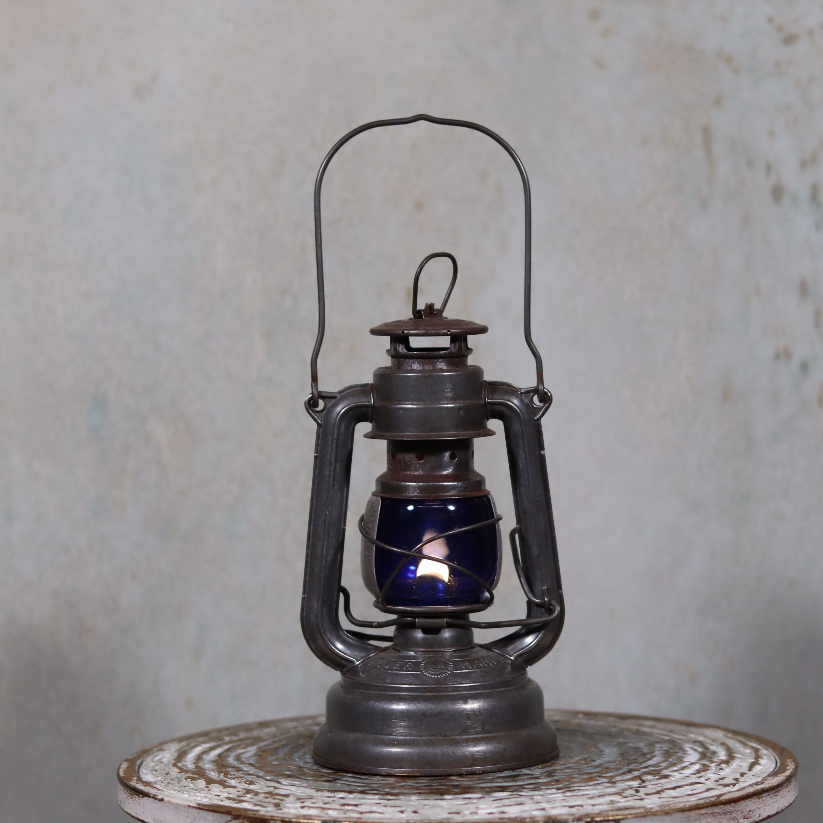 Vintage Feuerhand 176 Hurricane Lantern – 1960s – Superb Condition with Blue Glass & Reflector oil lamp displayed on rustic surface