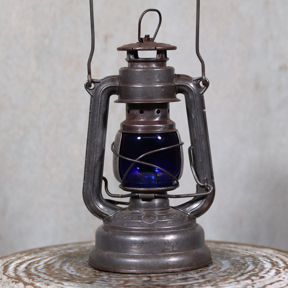 Vintage Feuerhand 176 Hurricane Lantern – 1960s – Superb Condition with Blue Glass & Reflector oil lamp displayed on rustic surface