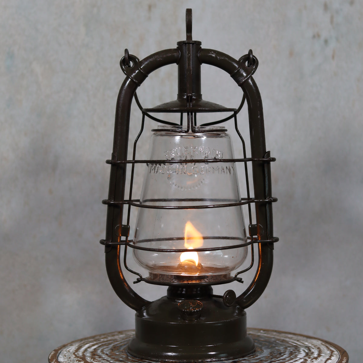 Vintage Feuerhand 323 Storm Lantern – Late 1930s, Original Paint & Embossed Glass with lit oil lamp flame and protective metal frame.