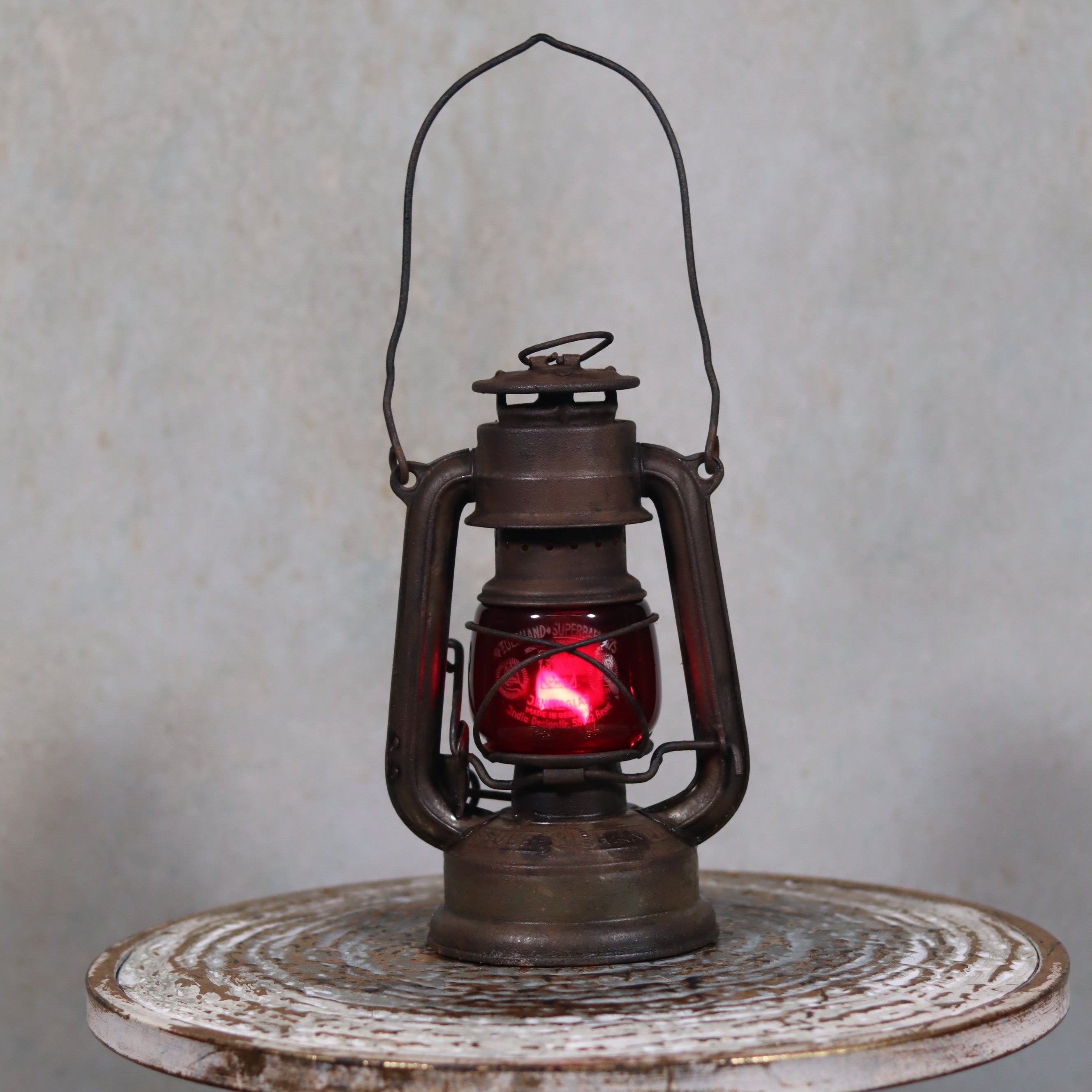 Vintage Pre-War Storm Lantern – Feuerhand 175 (1930s) with Red Glass oil lamp standing on rustic table background
