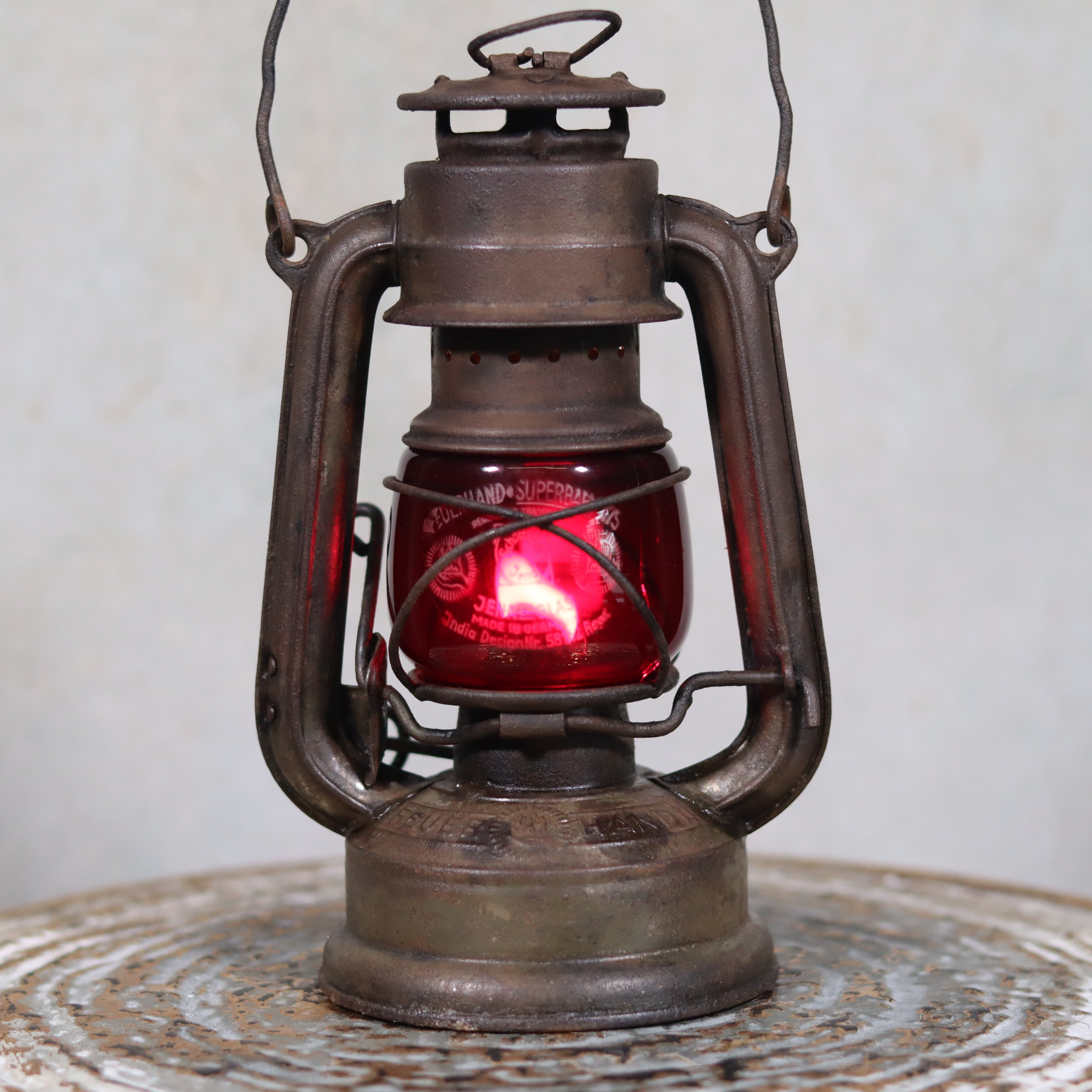 Vintage Pre-War Storm Lantern – Feuerhand 175 (1930s) with Red Glass oil lamp displayed on a textured surface