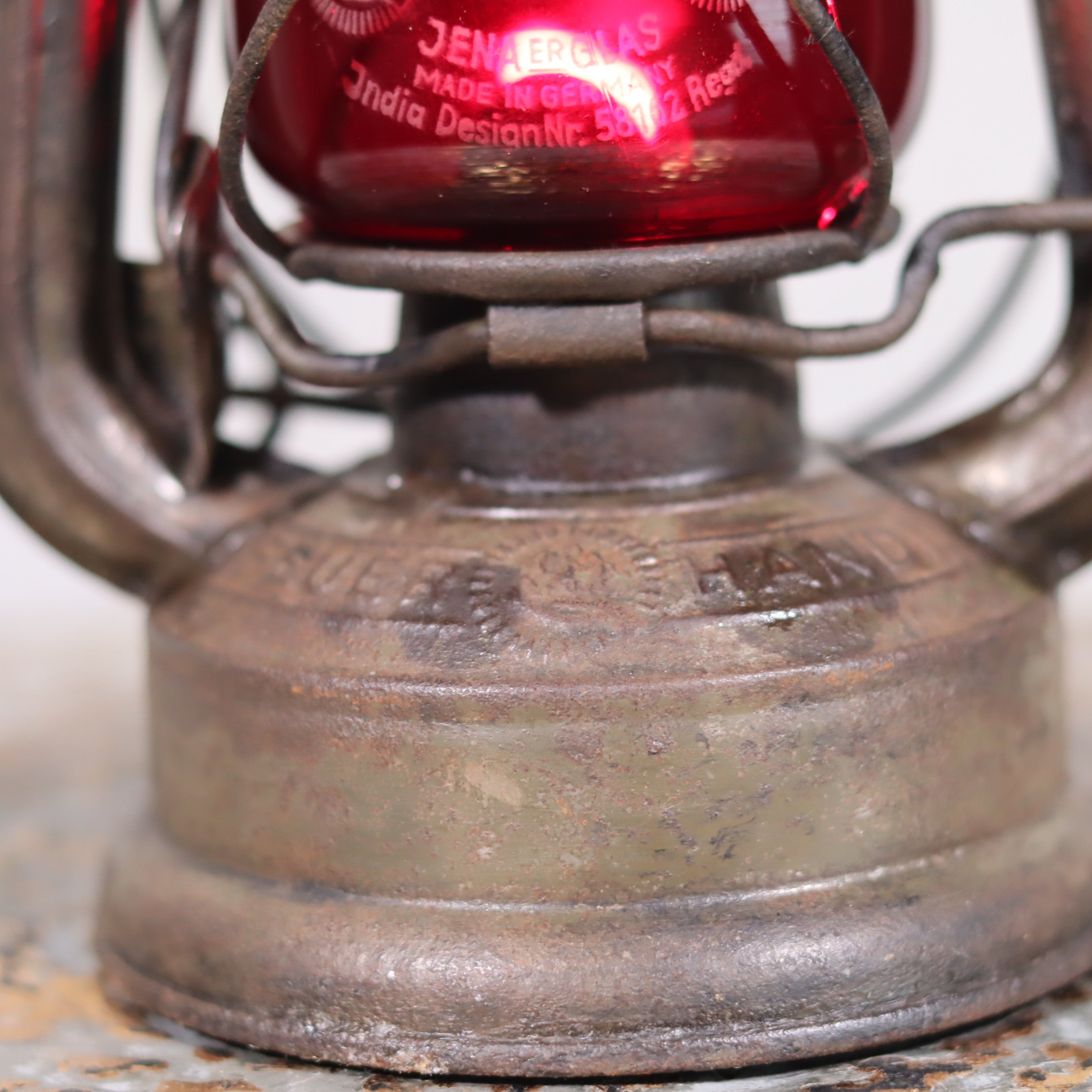 Close-up of Vintage Pre-War Storm Lantern – Feuerhand 175 (1930s) with Red Glass showing rusted metal base and glass details