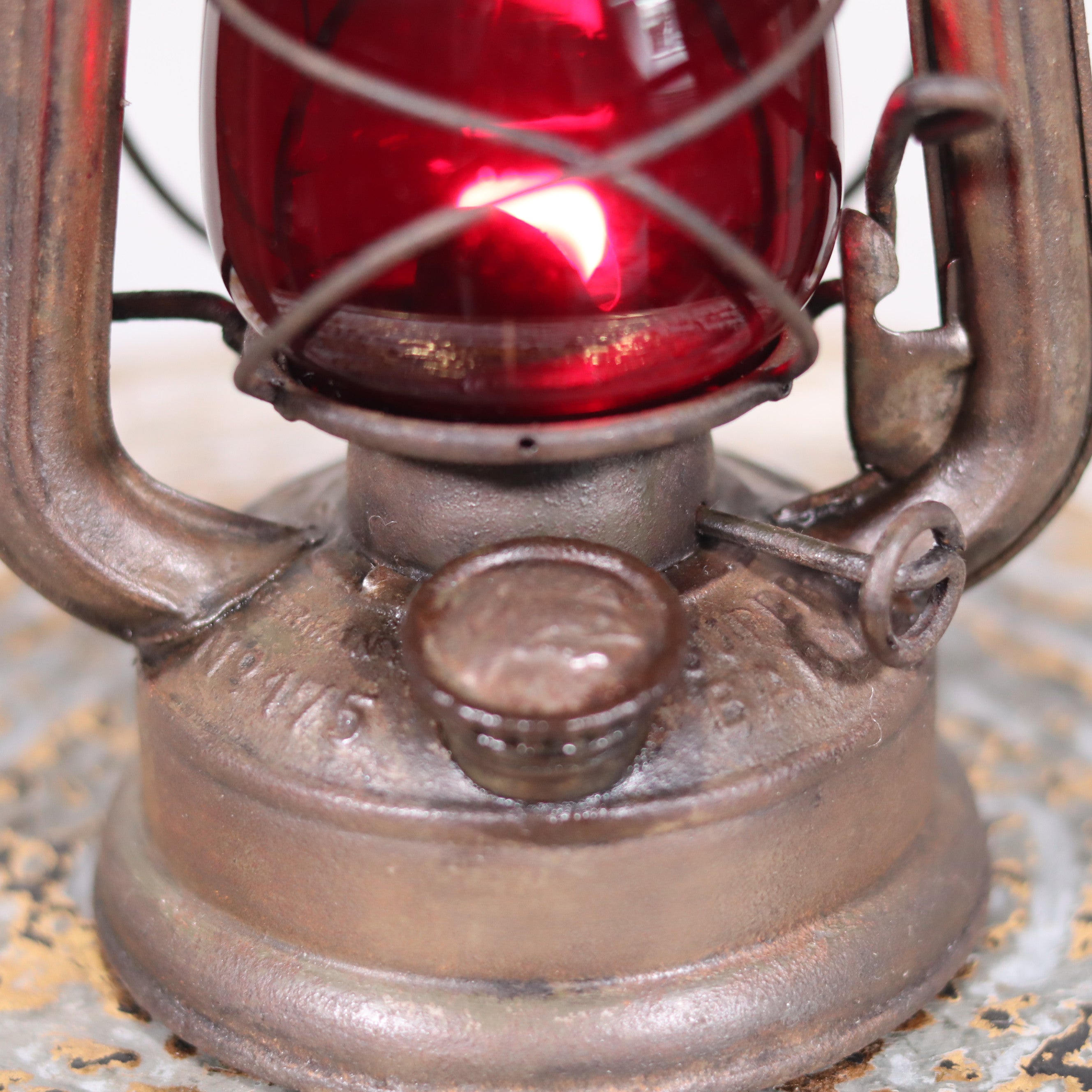 Close-up of the Vintage Pre-War Storm Lantern – Feuerhand 175 (1930s) with Red Glass metal base and wick adjustment knob.