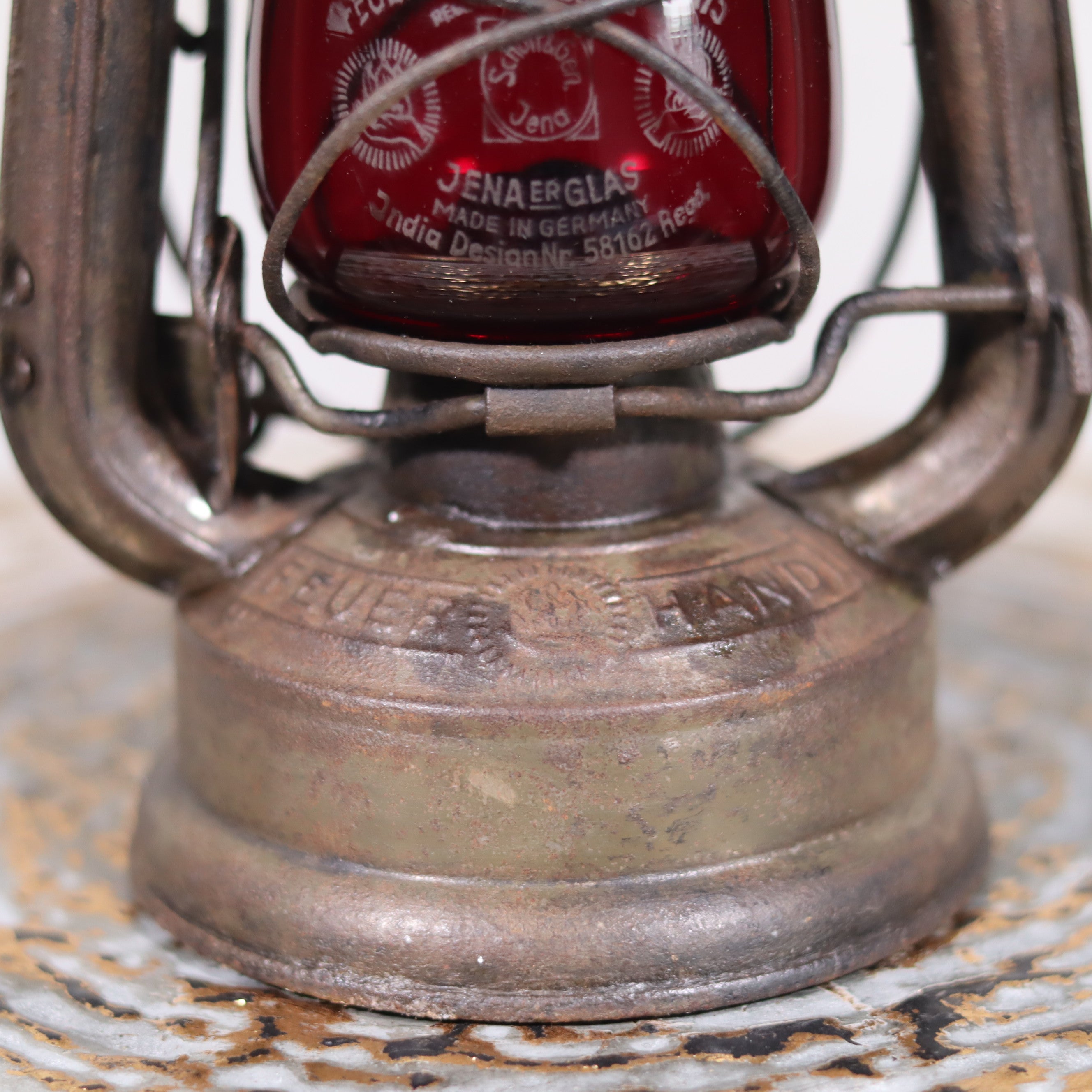 Close-up of vintage pre-war storm lantern – Feuerhand 175 (1930s) with red glass showcasing metal base details