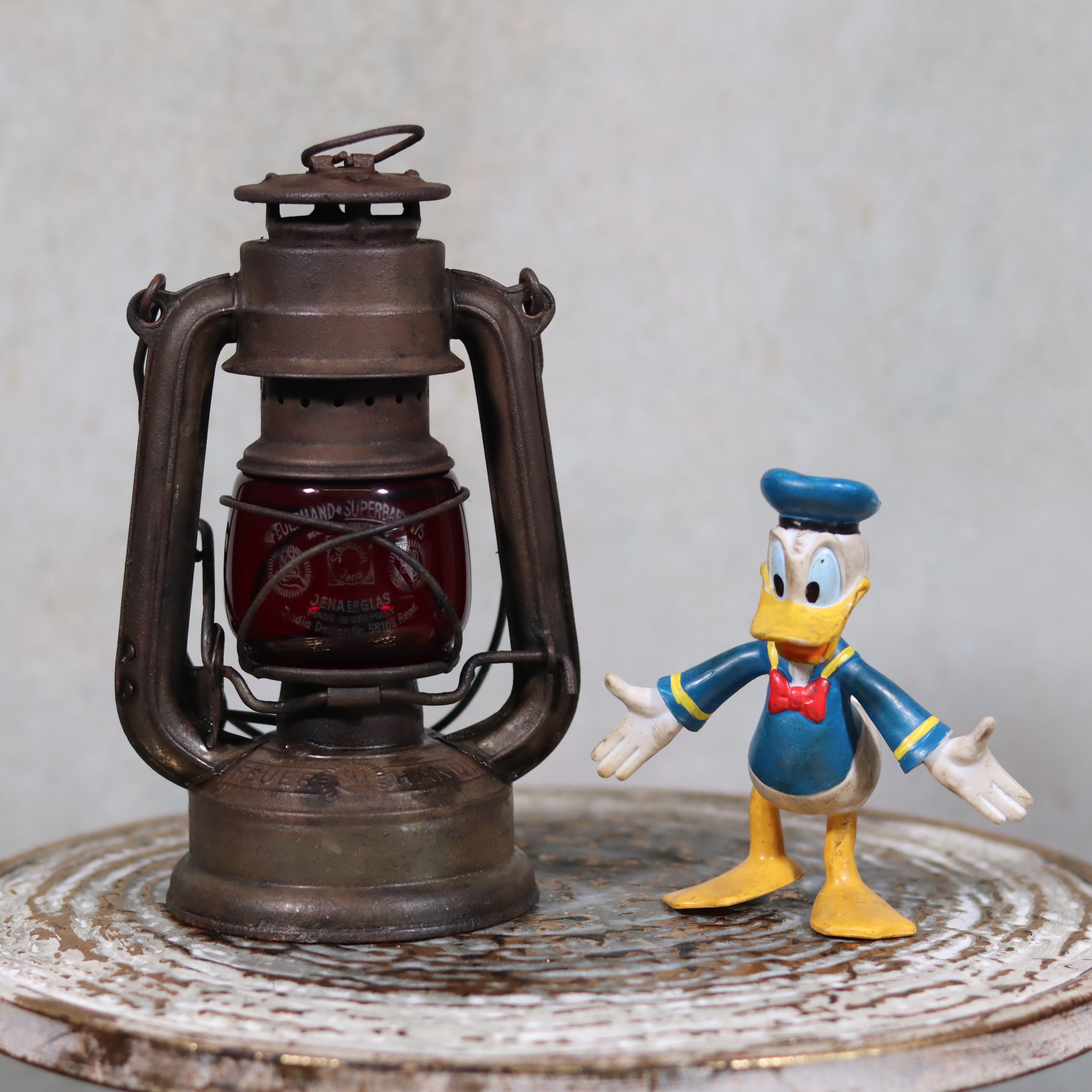 Vintage Pre-War Storm Lantern – Feuerhand 175 (1930s) with Red Glass oil lamp displayed beside a toy figure.