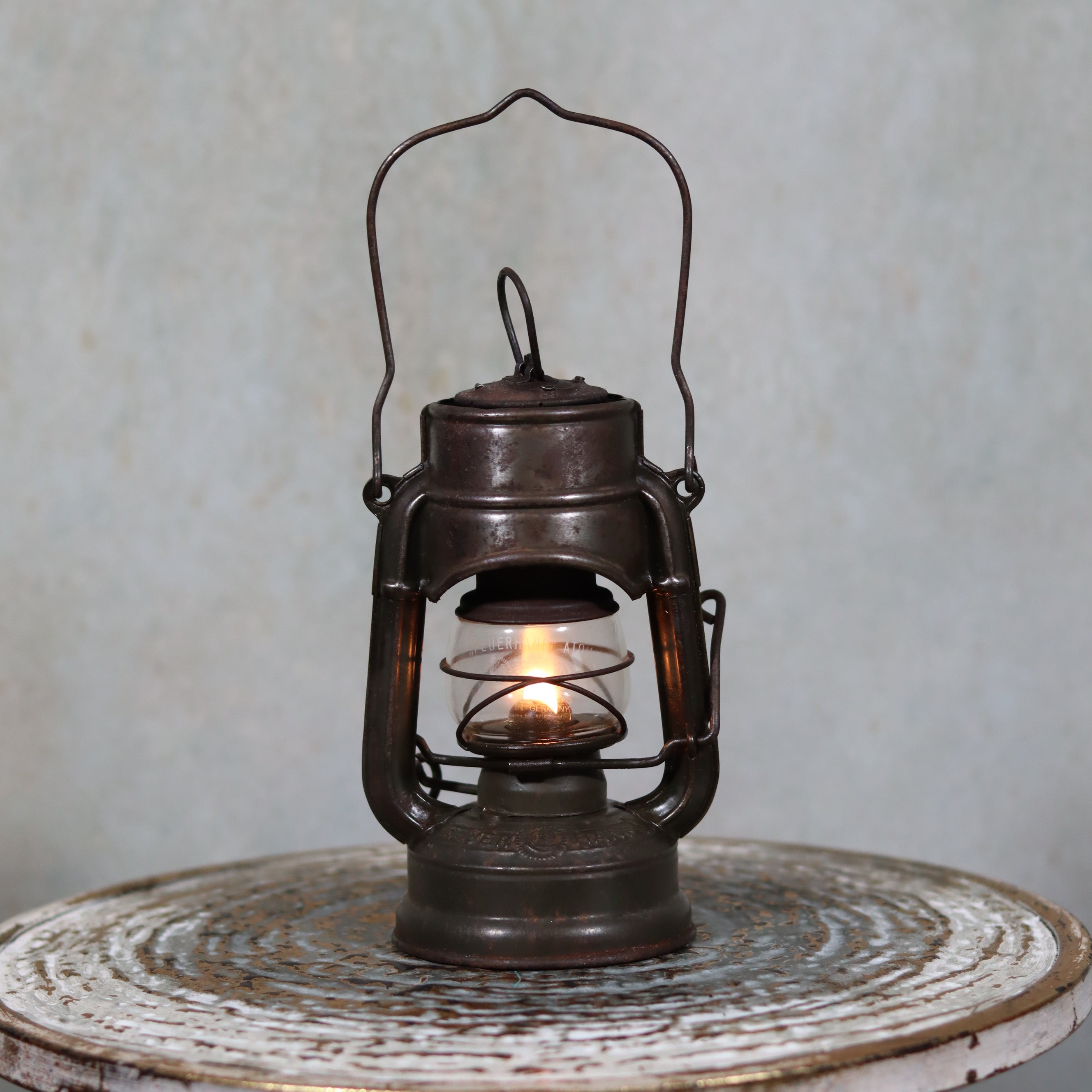 Beautiful and Functional Feuerhand “Atom 75 STK” Storm Lantern – Pre-War, Late 1930s to Early 1940s vintage oil lamp lit on wooden surface