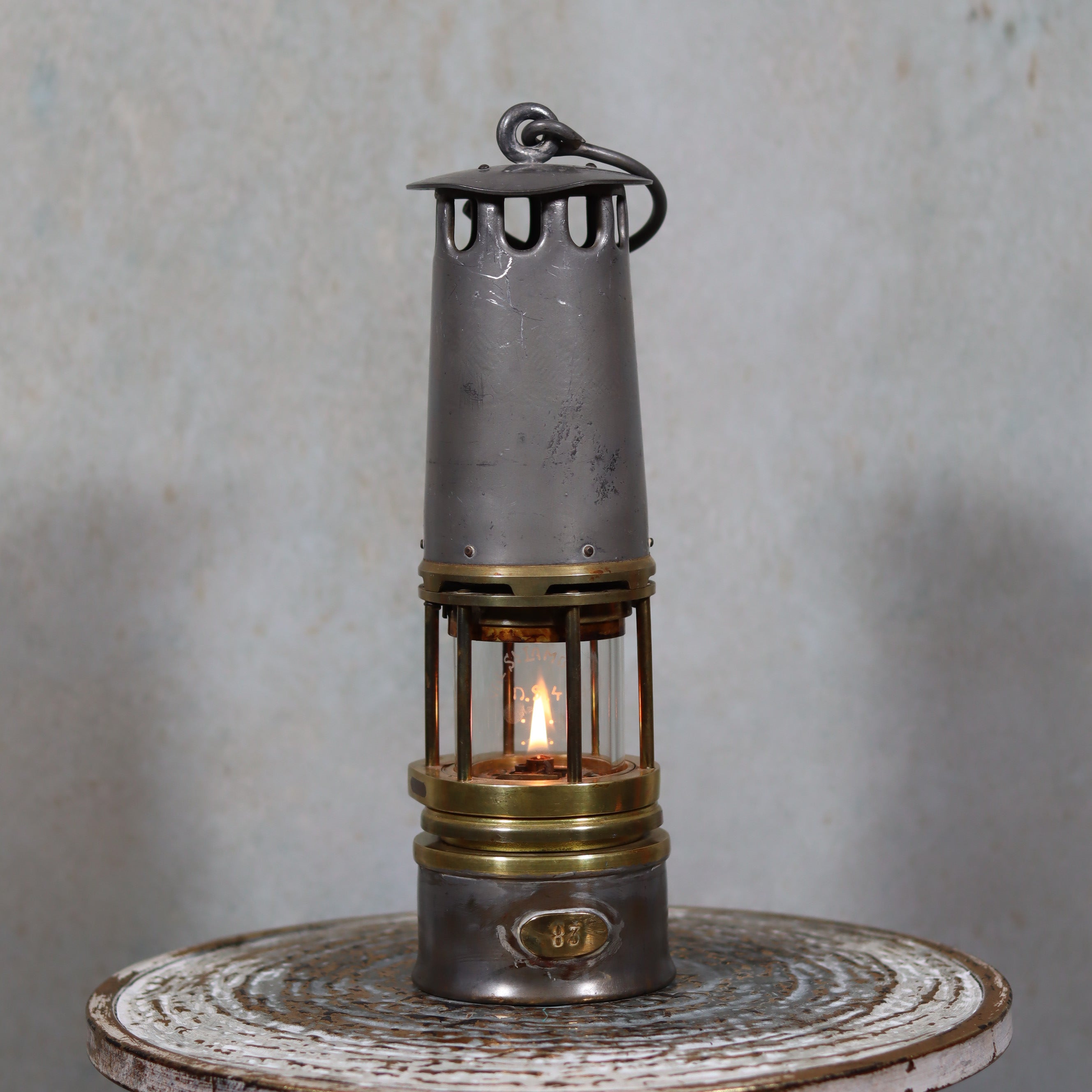Beautiful, Almost Unused Miner’s Lamp by Hubert Joris (ca. 1900) with Val St. Lambert Glass showing lit oil lamp on rustic table