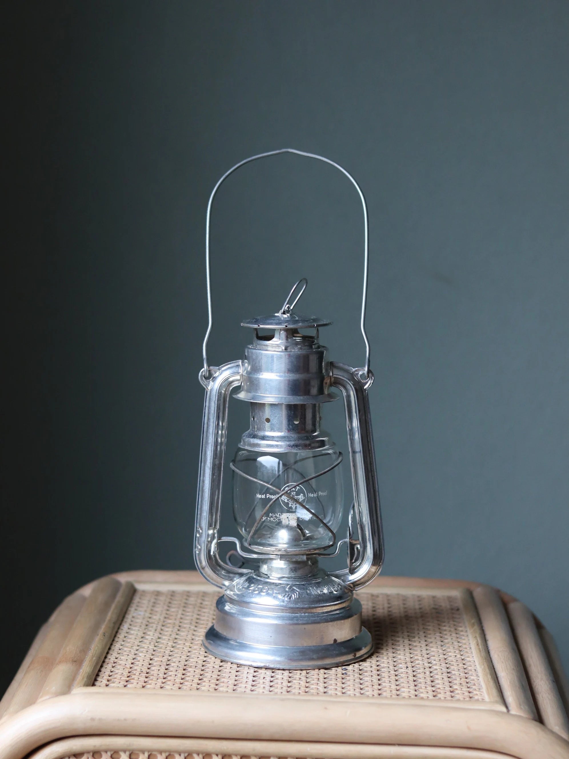 Rare New Old Stock Mewa Hurricane Lantern – BAT 259 (1970s/80s) oil lamp in polished metal with glass chimney on wicker surface