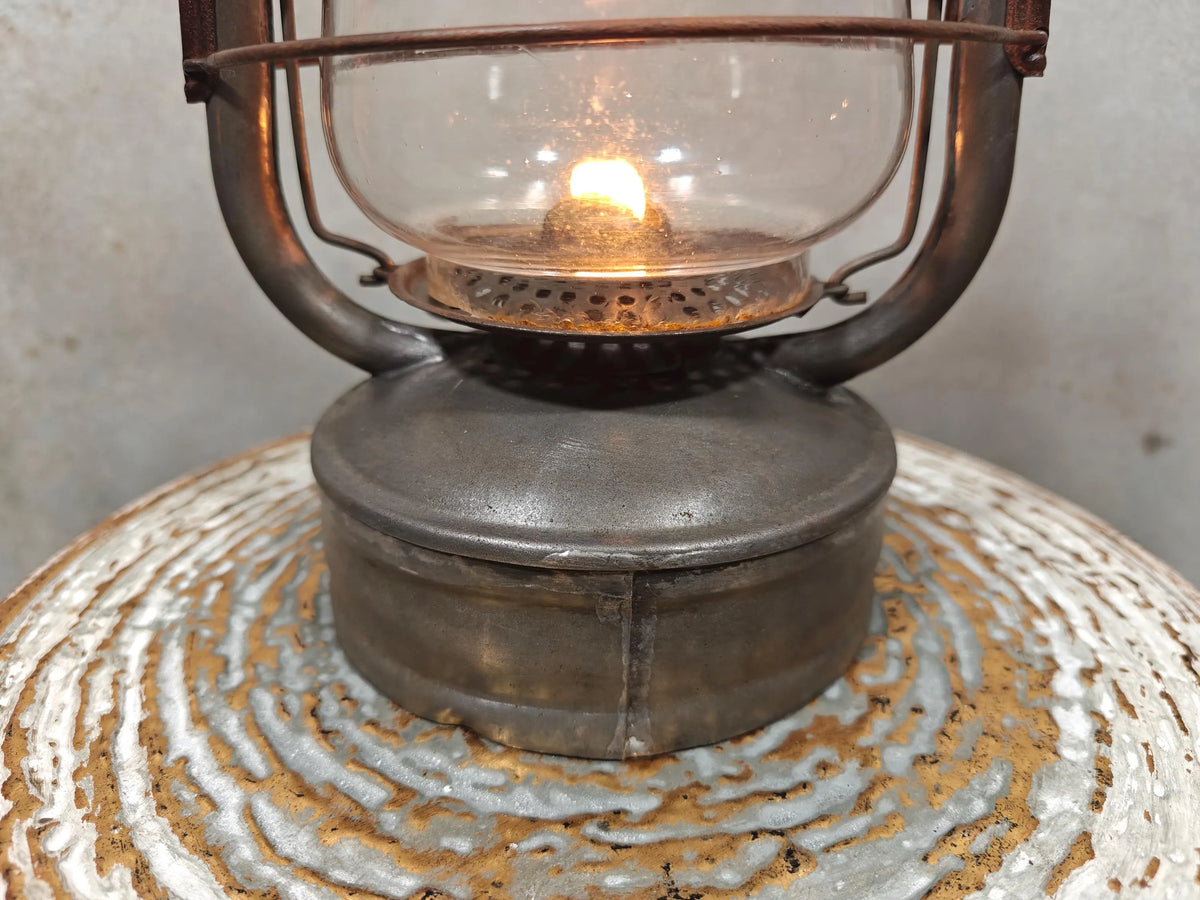 Vintage English Hurricane Lantern – Brass Tank Cap, 1930s Design oil lamp lit on rustic textured surface