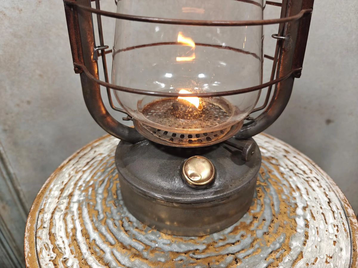 Vintage English Hurricane Lantern – Brass Tank Cap, 1930s Design oil lamp with lit flame and rustic metal base detail