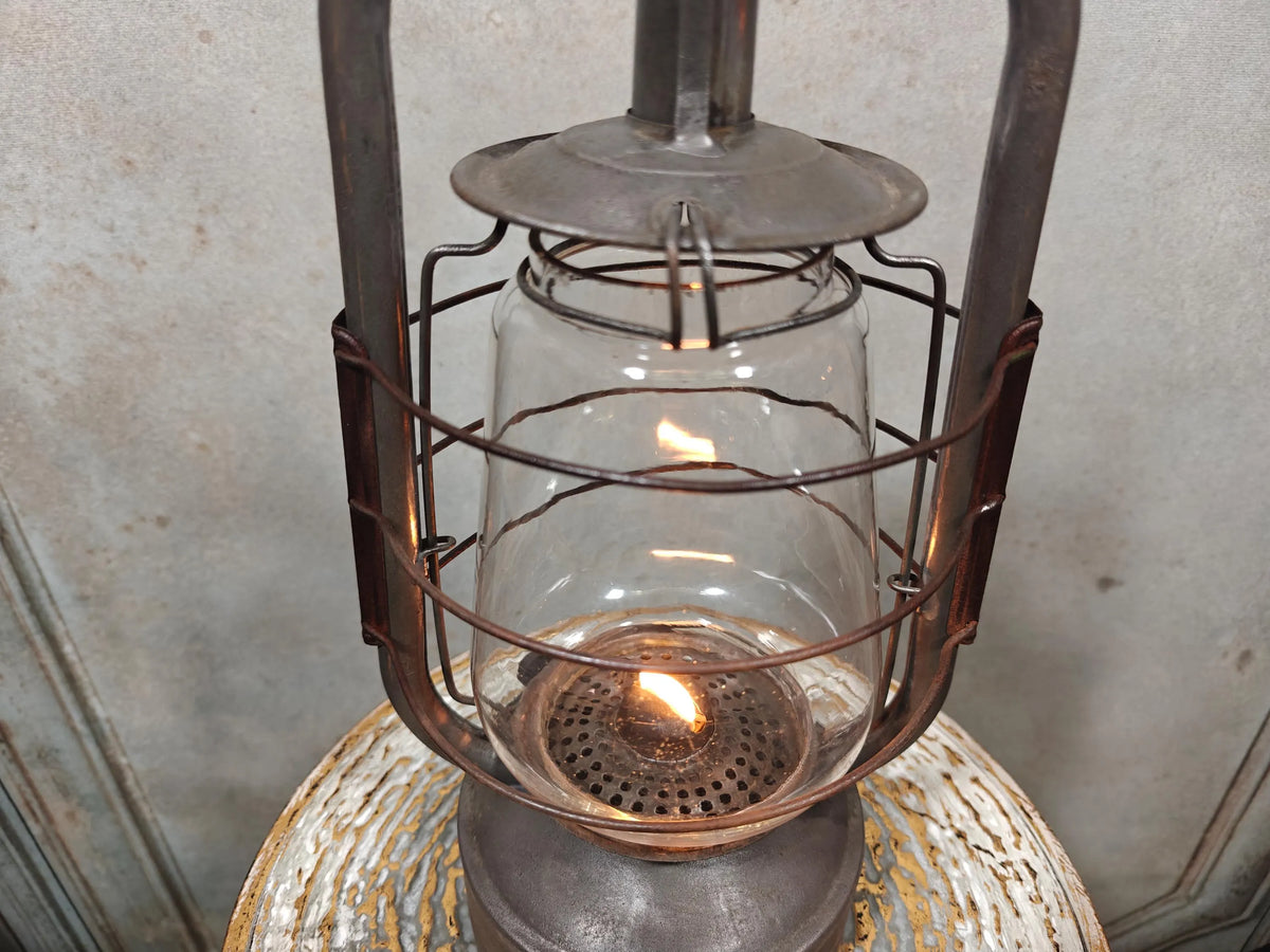 Vintage English Hurricane Lantern – Brass Tank Cap, 1930s Design glowing with oil lamp flame and rustic metal frame detail