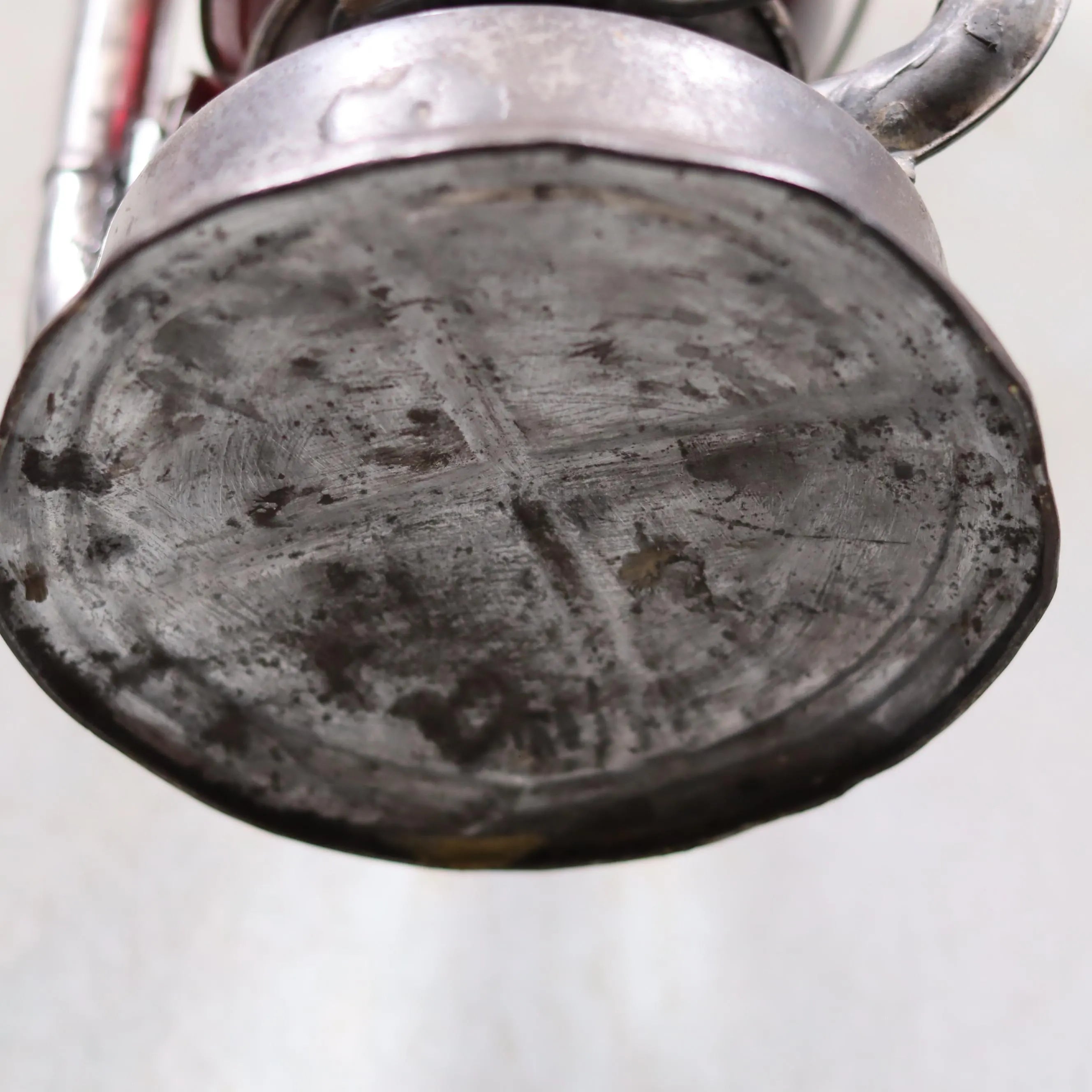 Close-up view of the base of the Rare Canadian Beacon Hurricane Lantern – Vintage Red Glass Kerosene Lamp showing metal wear.